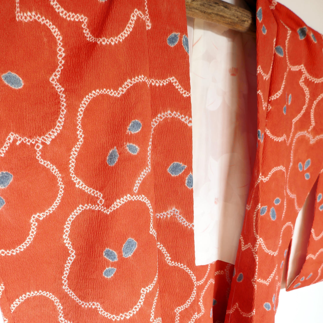 Haori vintage japonais en soie orange à motifs floraux blancs et bleus, époque Shōwa – détail de la doublure visible.