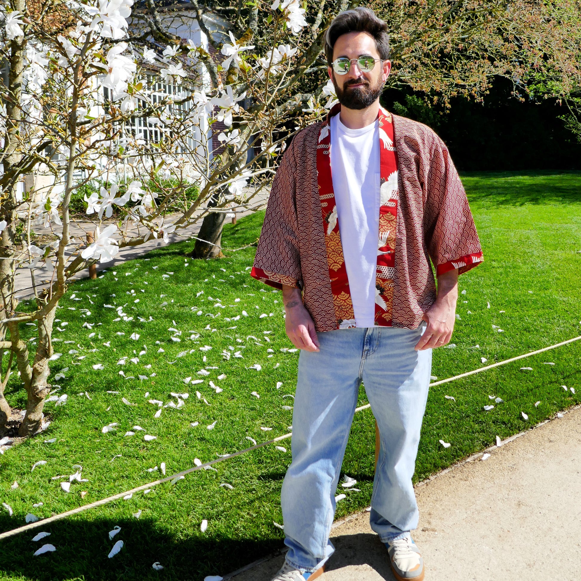 Tôma porte le haori japonais Akane Tsuru avec un t-shirt blanc et un jean clair, dans un style casual oversize au jardin.