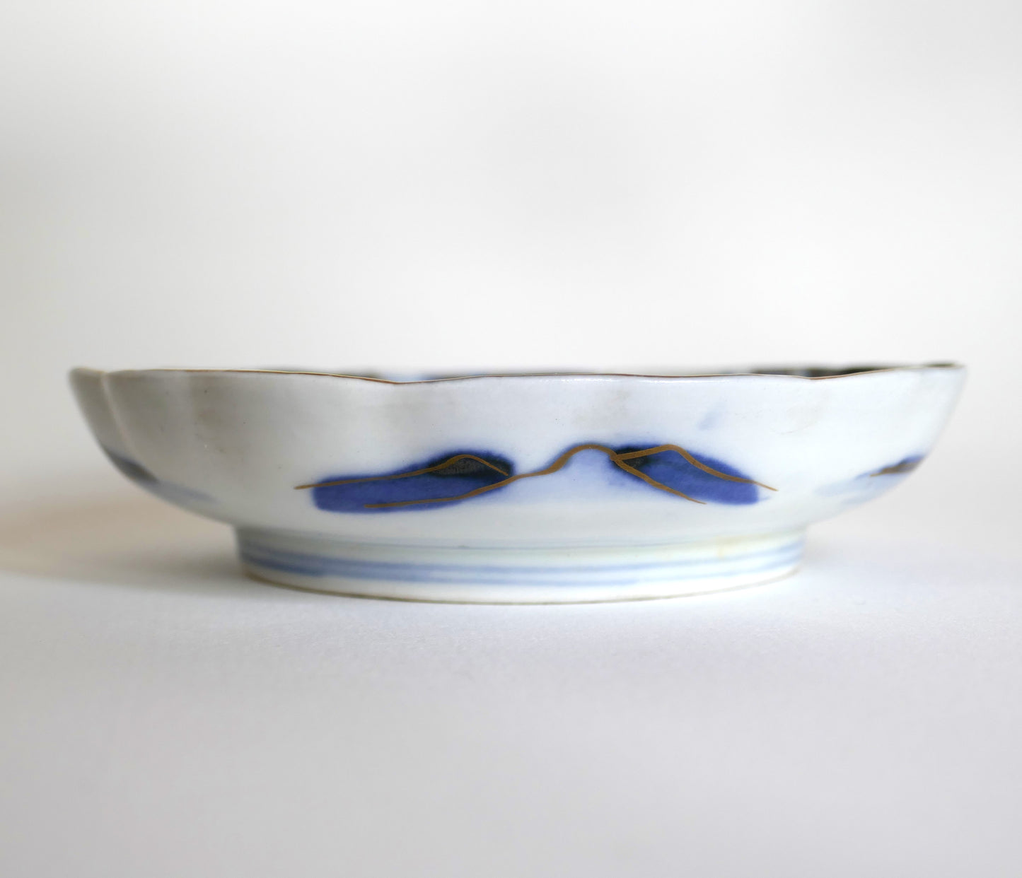 Vue latérale du décor bleu et or sur le flanc d’une assiette ondulée Arita Meiji