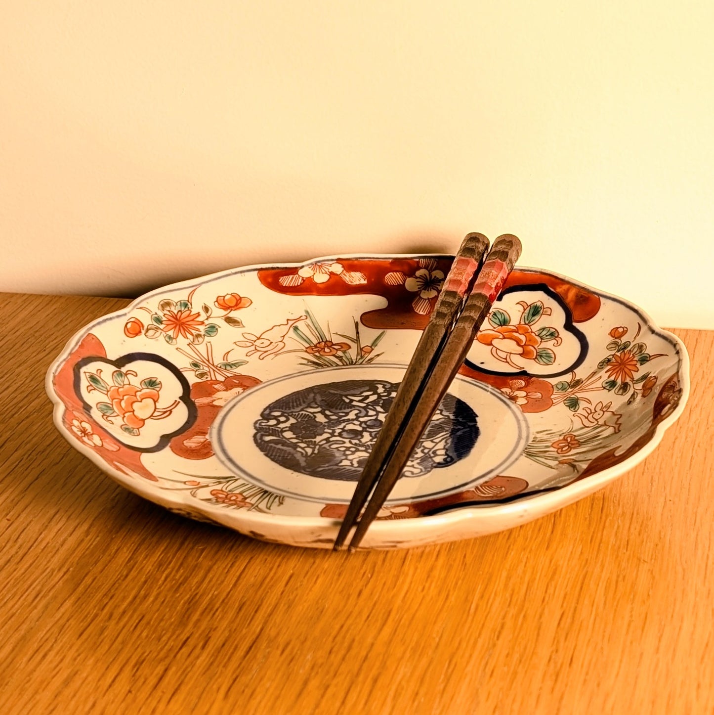 Assiette japonaise antiquité Imari en situation d’art de la table avec baguettes, décor floral et lapin