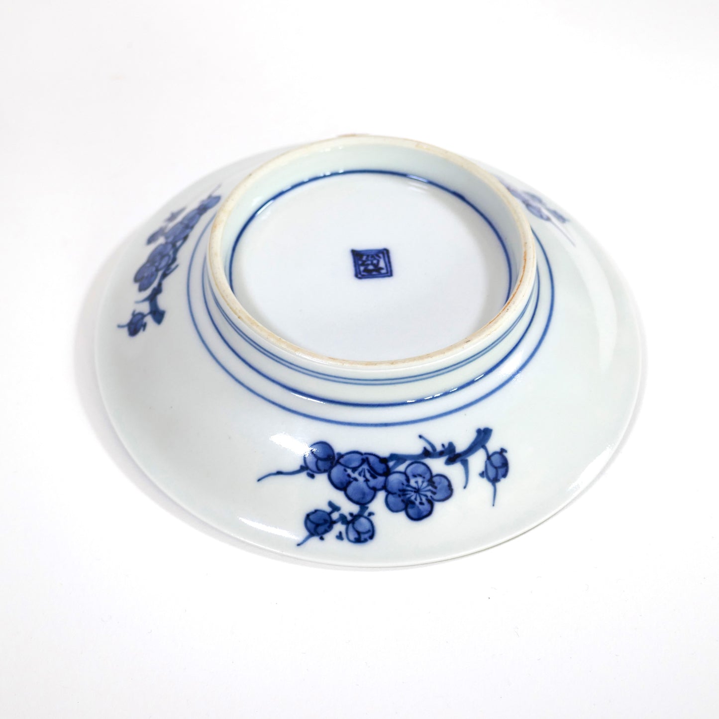 Assiette Imari Arita, vue en contre-plongée valorisant la brillance du glaçage et les filets concentriques sous le pied