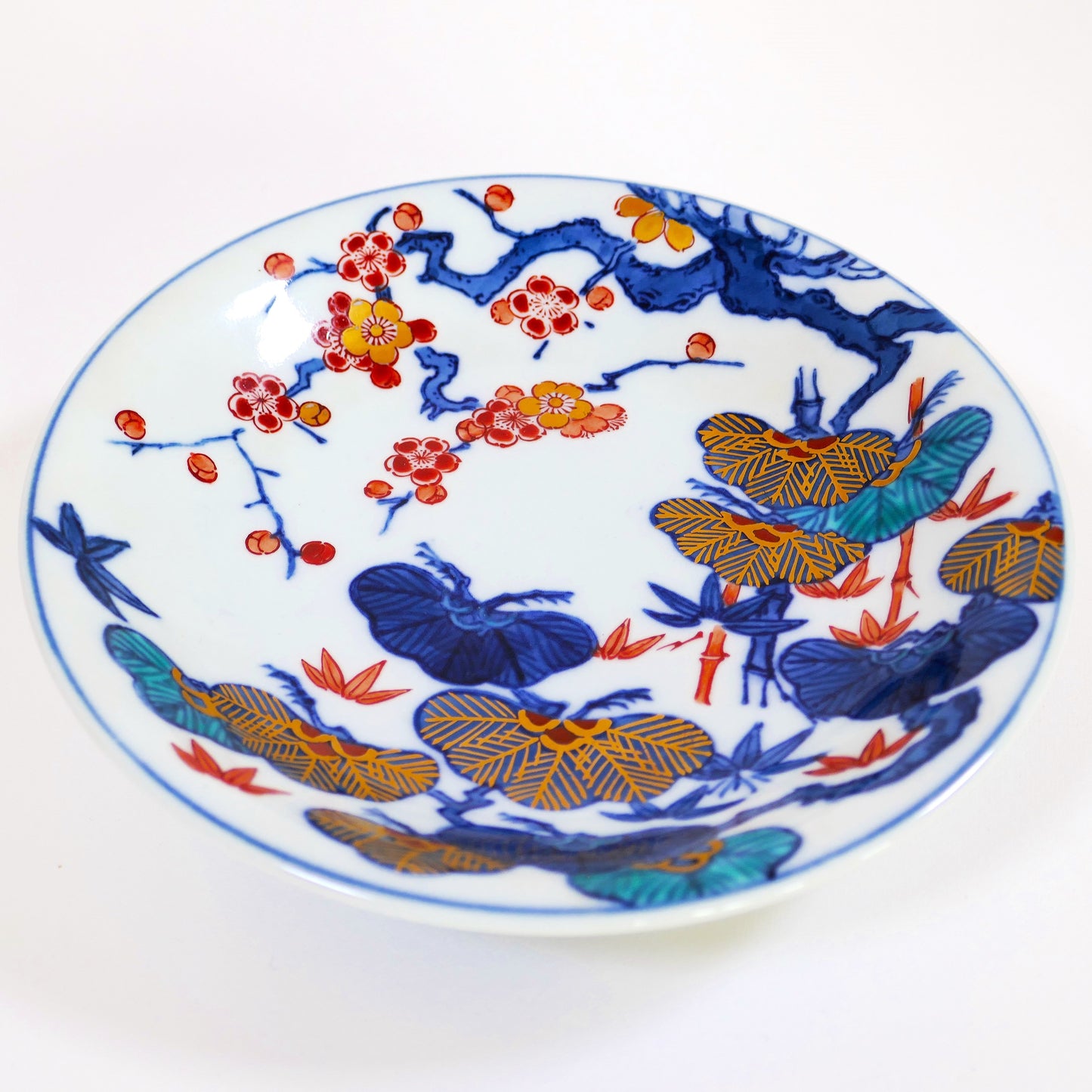 Assiette Imari Arita, vue oblique montrant la finesse de la porcelaine et les motifs Sho Chiku Bai en émaux polychromes et dorures