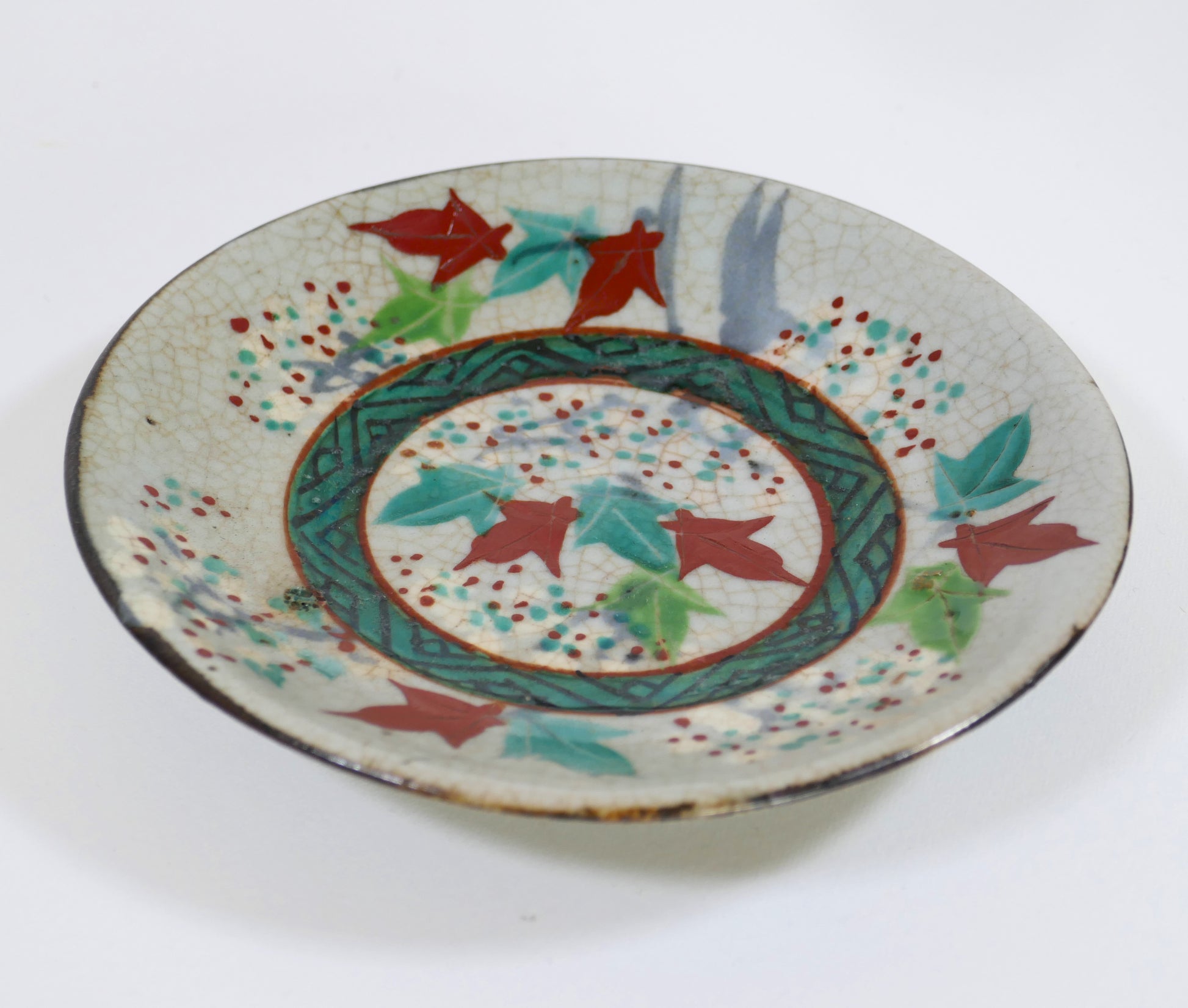 Assiette japonaise Inuyama-yaki de l'époque Edo, décorée de feuilles d'érable rouges et vertes (momiji), vue de profil avec émail craquelé.