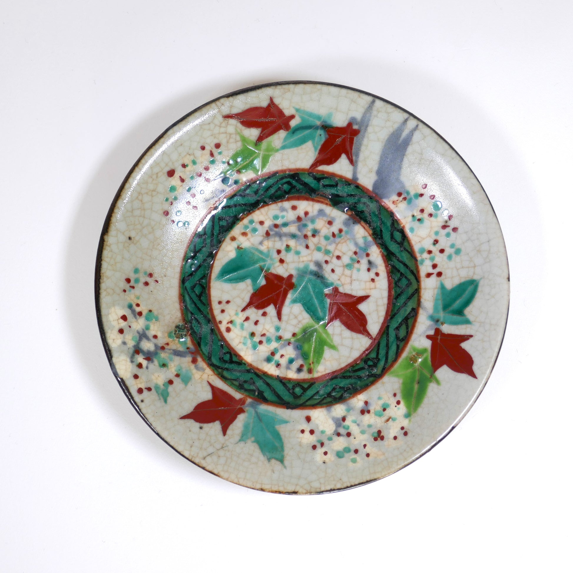 Assiette japonaise Inuyama-yaki de l'époque Edo, décorée de feuilles d'érable rouges et vertes (momiji), vue de profil avec émail craquelé.