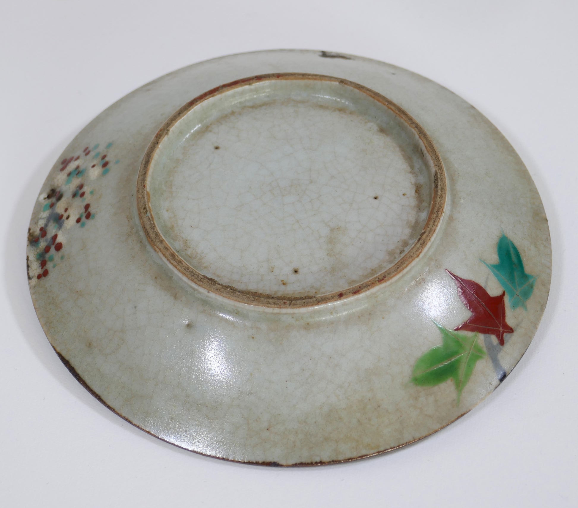 Dos d'une assiette ancienne Inuyama-yaki de l'époque Edo, montrant un émail craquelé et un décor floral discret.