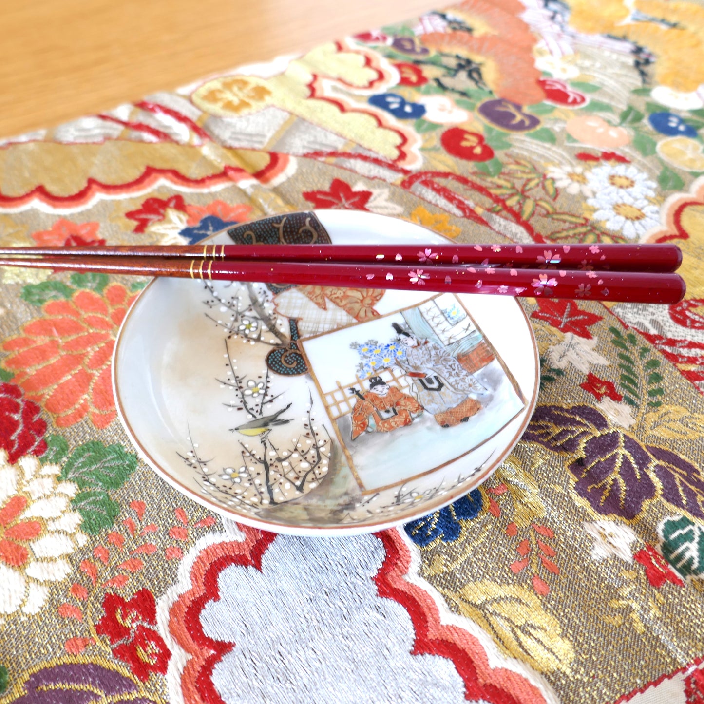 Assiette japonaise Kutani avec baguettes rouges à motif sakura et nappe en tissu brodé
