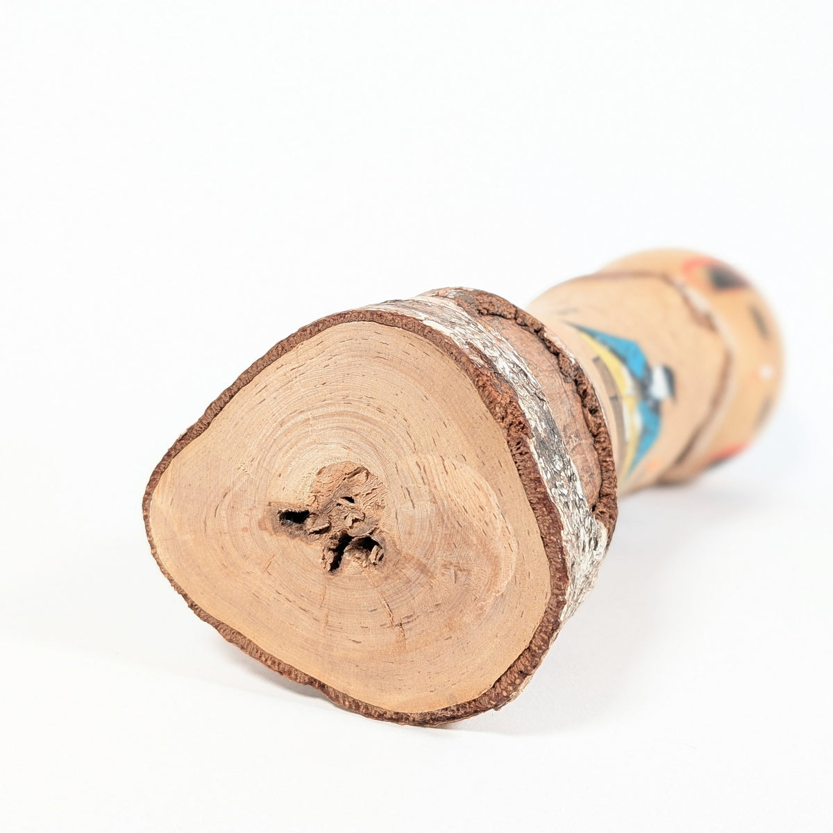 Base en bois massif d’une kokeshi japonaise vintage, montrant les cernes du bois et l’écorce naturelle conservée