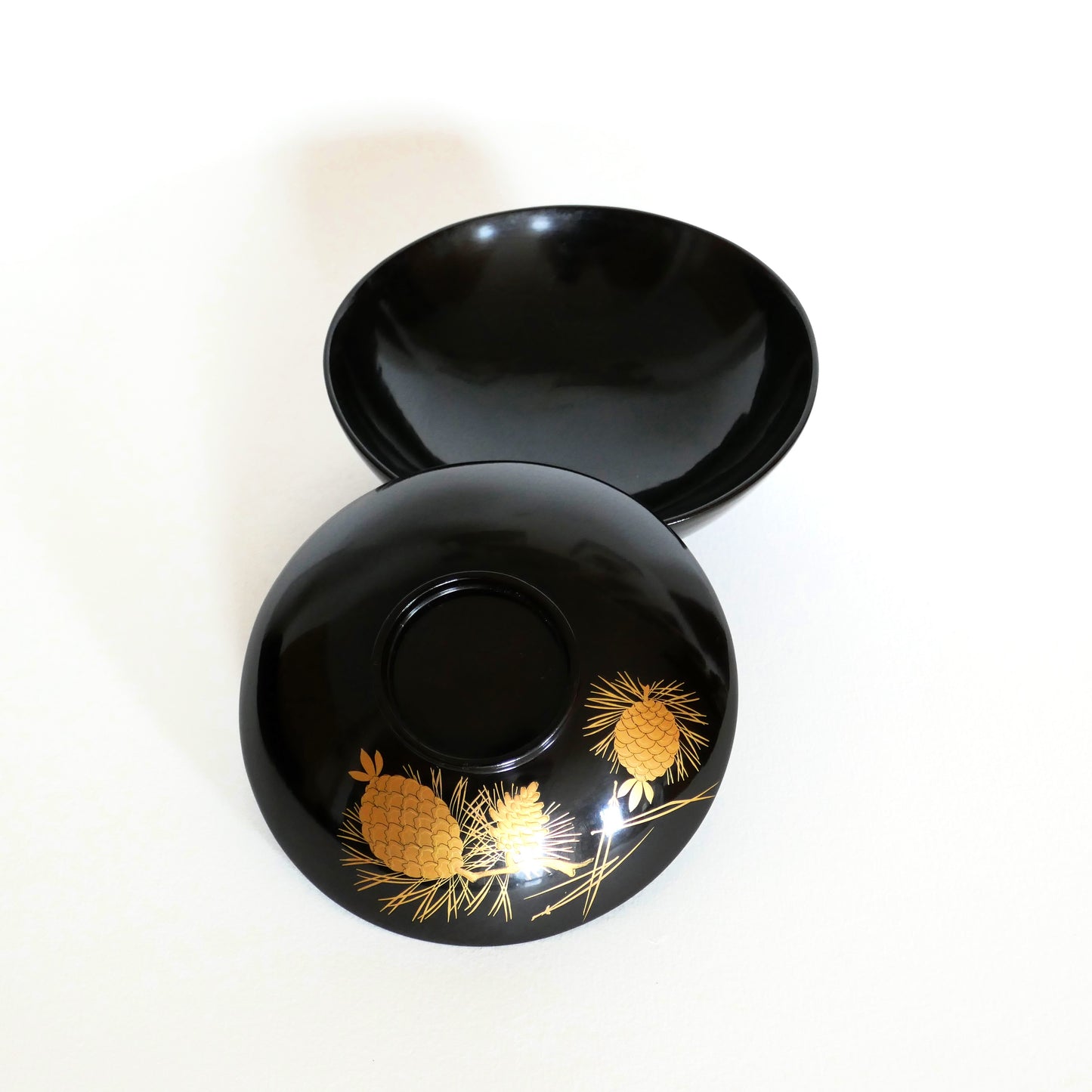 Vue intérieure d’un bol japonais en laque noire, avec son couvercle décoré de pins dorés – vaisselle traditionnelle