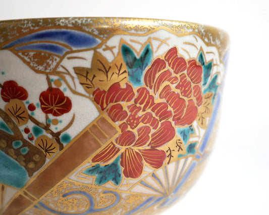 Détail du bol à matcha japonais montrant une pivoine botan rouge, des fleurs de prunier et un éventail rehaussé d’or.