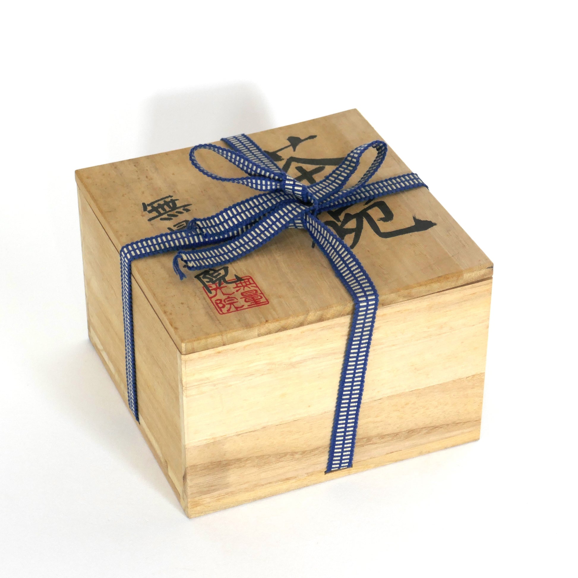 Boîte tomobako traditionnelle en bois fermée, contenant un chawan japonais. Corde bleue et calligraphie noire avec sceau rouge.