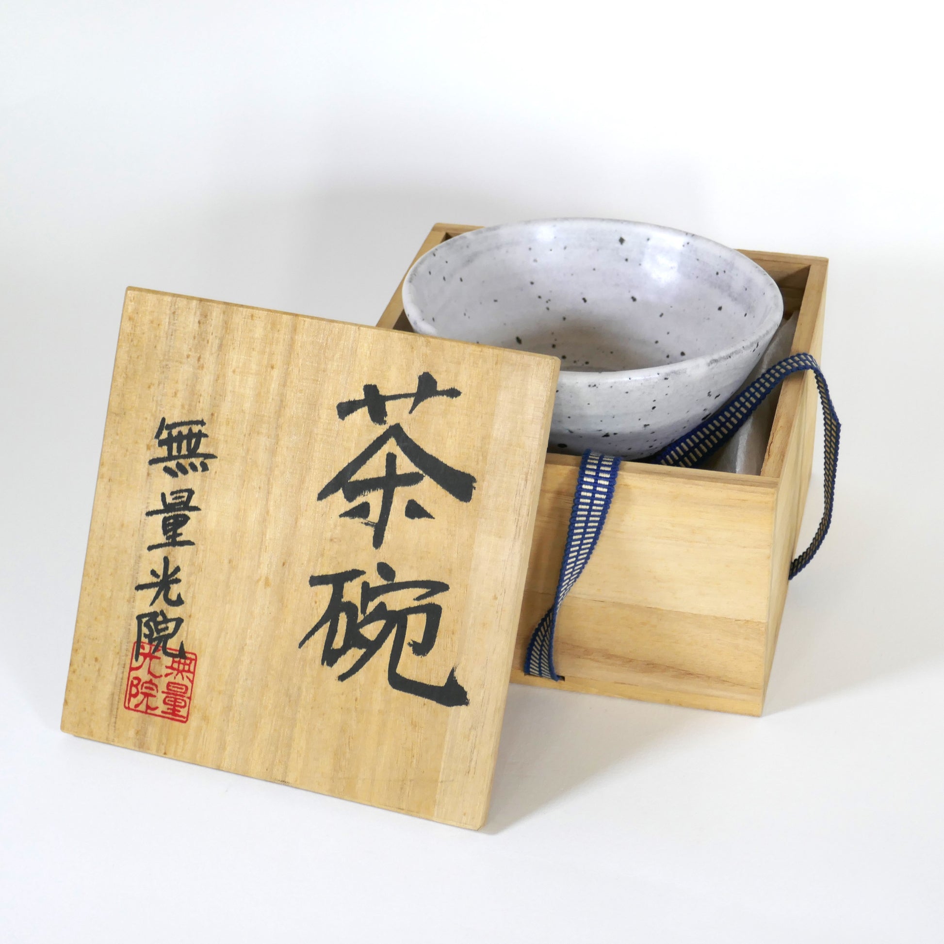 Bol à thé en grès blanc présenté dans sa boîte en bois ouverte, couvercle calligraphié incliné sur le côté
