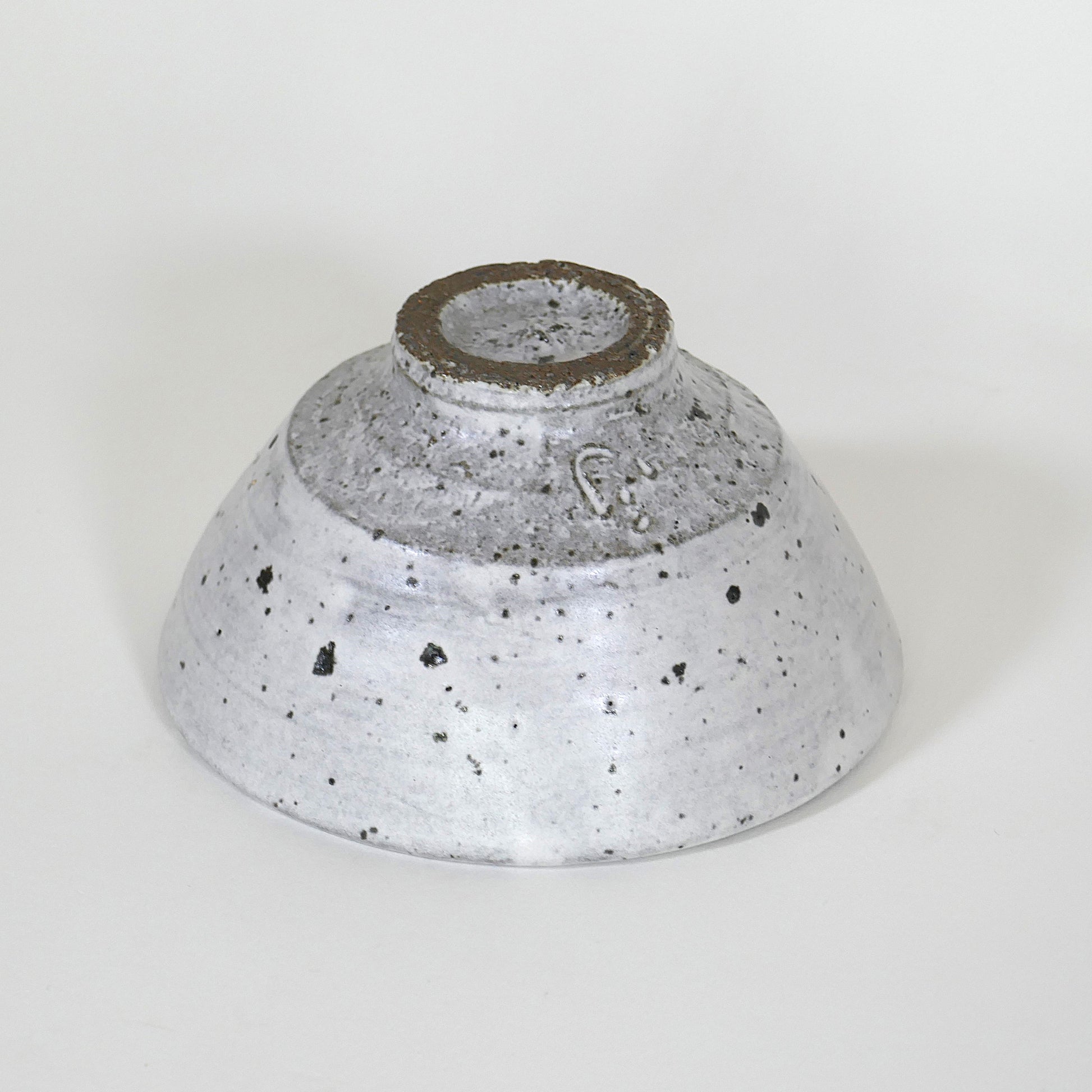 Pied du chawan laissé brut, glaçure blanche mouchetée s’arrêtant net, signature du potier en creux.