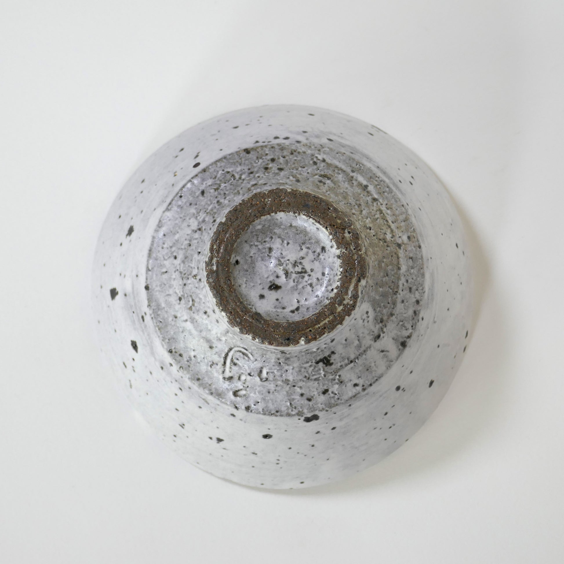 Vue du dessous du bol, exposant un pied brut taillé à vif dans le grès, sans émaillage.