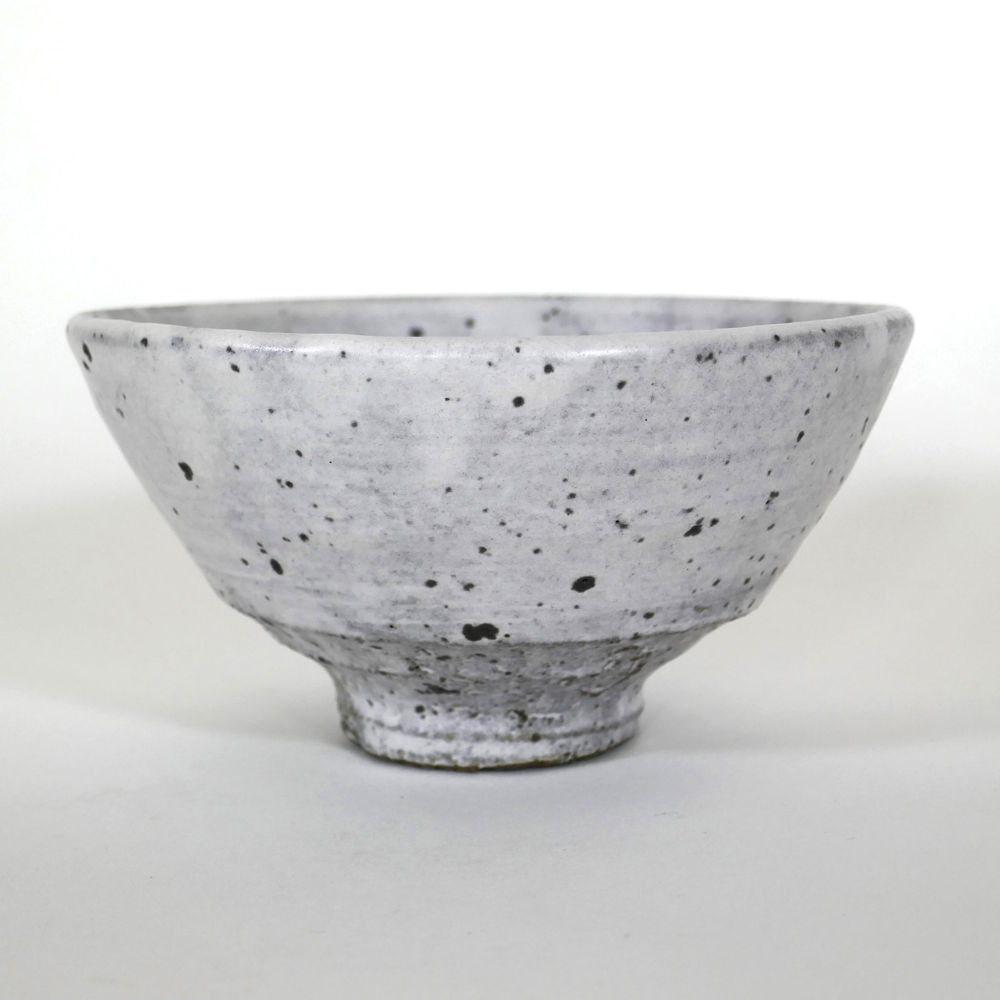 Profil complet du chawan montrant sa silhouette évasée et ses surfaces mouchetées aux tons minéraux.