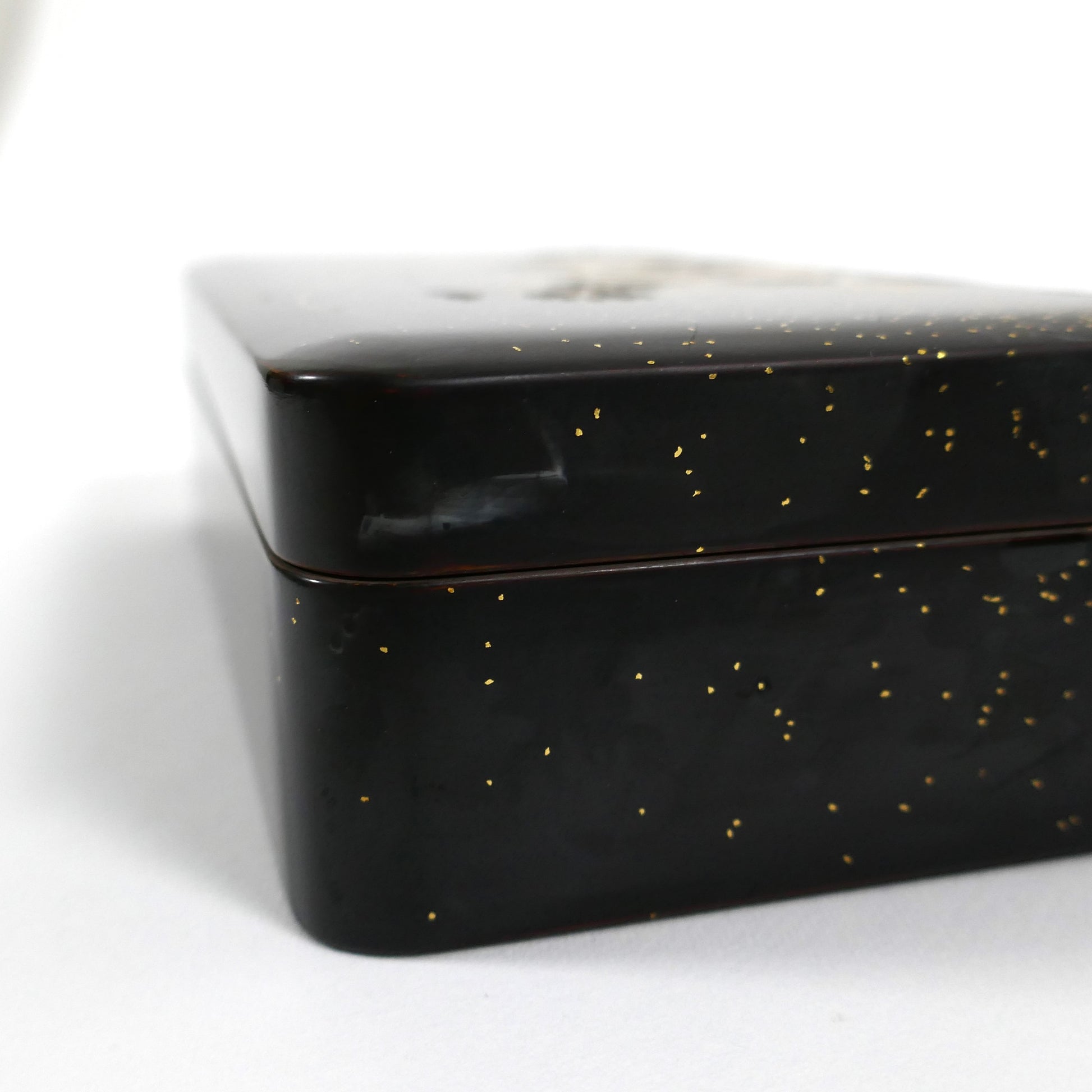 Détail du coin de la boîte en laque noire japonaise, finition brillante avec éclats de poudre d’or.