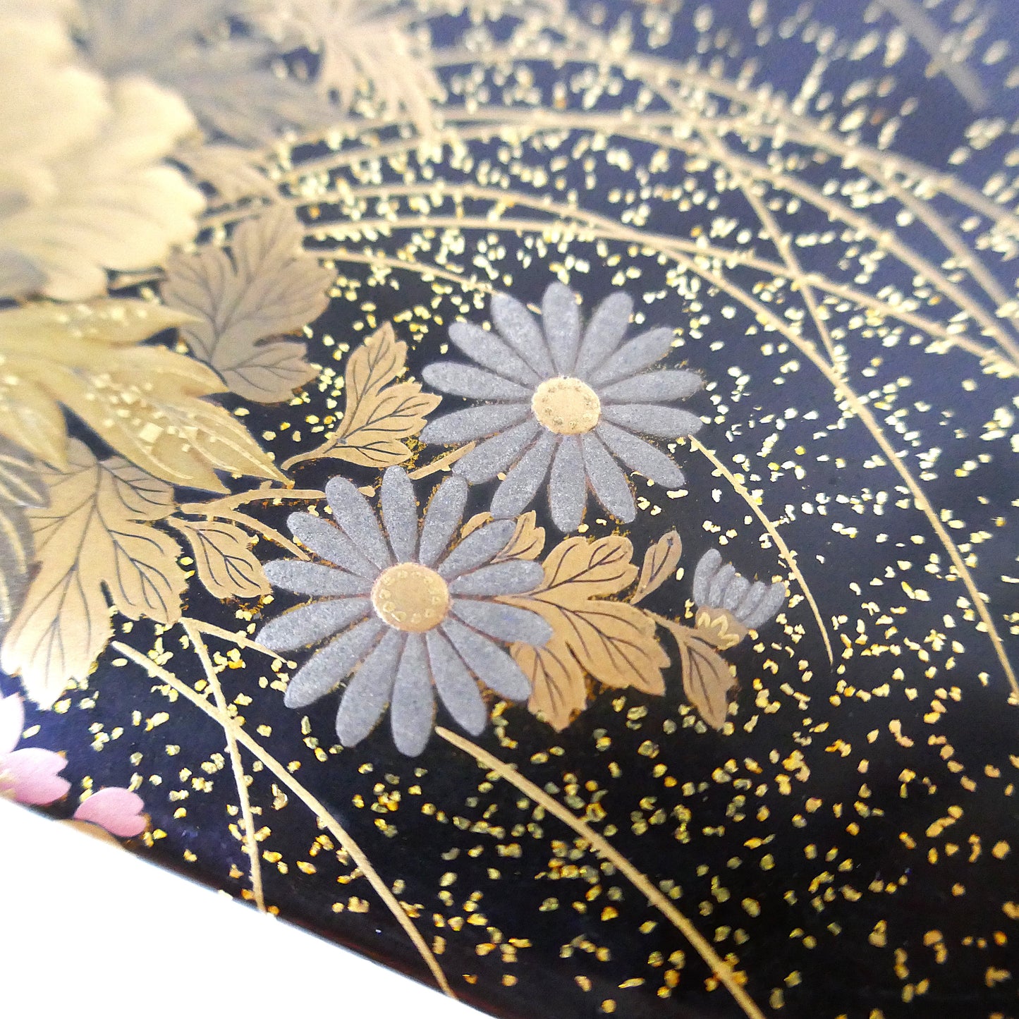 Détail de chrysanthèmes en argent maki-e sur laque noire Zohiko Kyoto, artisanat Taishō.