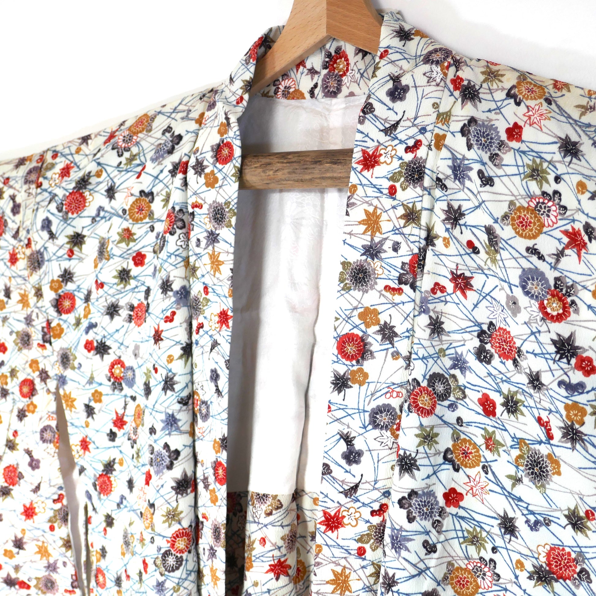 Zoom sur l’ouverture d’un haori vintage en soie blanche, motifs d’automne kiku 菊 et momiji 紅葉.