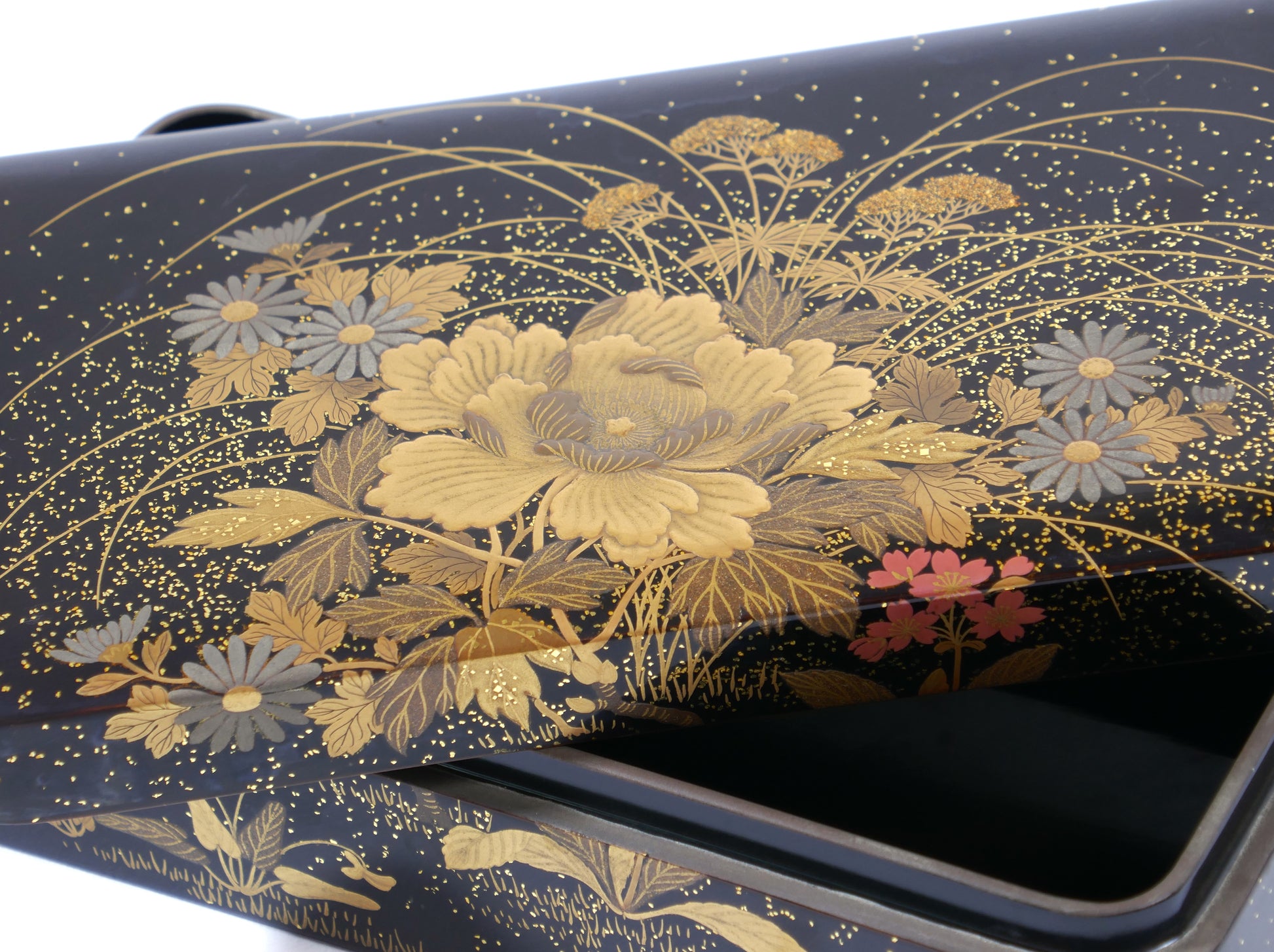 Gros plan sur la décoration florale dorée en maki-e sur boîte japonaise Zohiko Kyoto, artisanat urushi traditionnel.