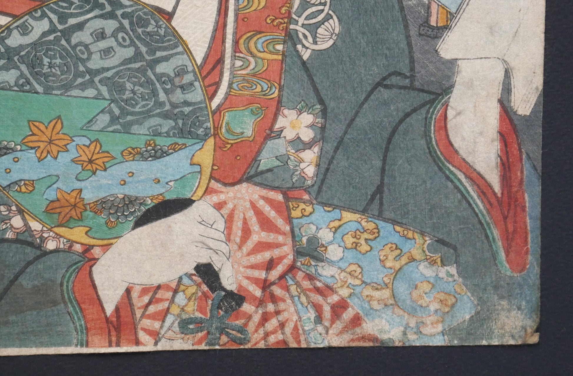 Détail du kimono, de l’éventail et de la main d’Okaru dans l’estampe.