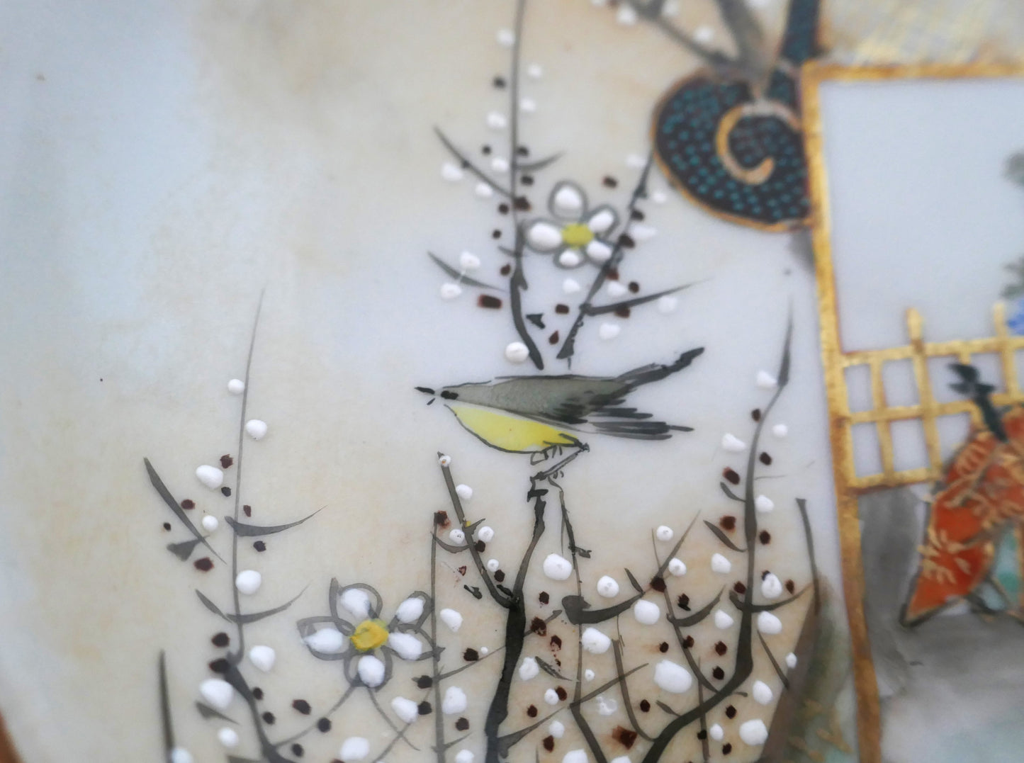 Détail d’un oiseau et de fleurs de prunier en émail blanc en relief sur une assiette Kutani