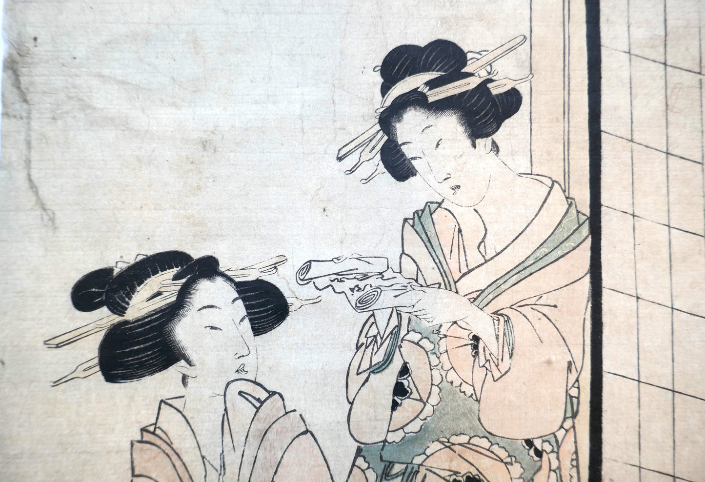Détail de deux courtisanes manipulant un rouleau de papier dans une estampe bijin-ga de Kikugawa Eizan.