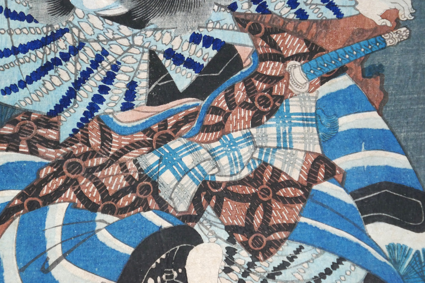 Zoom sur les motifs textiles complexes du kimono et sur le katana du guerrier Higuchi Jirō Kanemitsu dans une estampe de Yoshiiku, 1863, série Imayō Nazorae Genji, chapitre Matsukaze.
