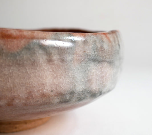 Gros plan du bord irrégulier d’un chawan aka raku avec émail craquelé rose et rouge