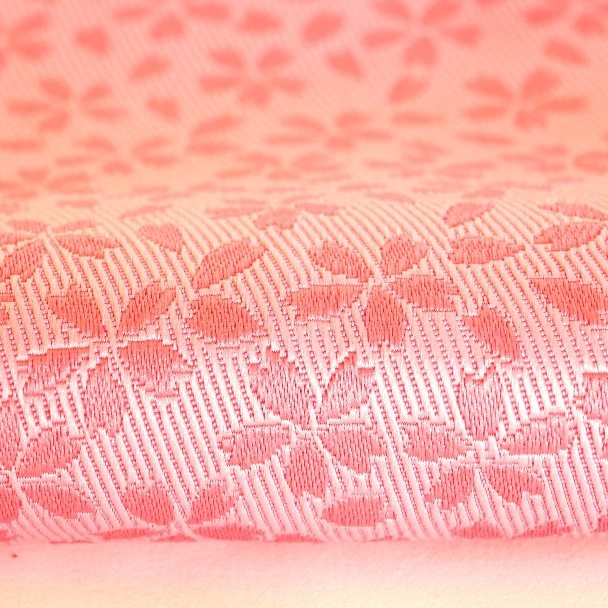 Détail de la texture du tissu rose à motifs sakura tissés.