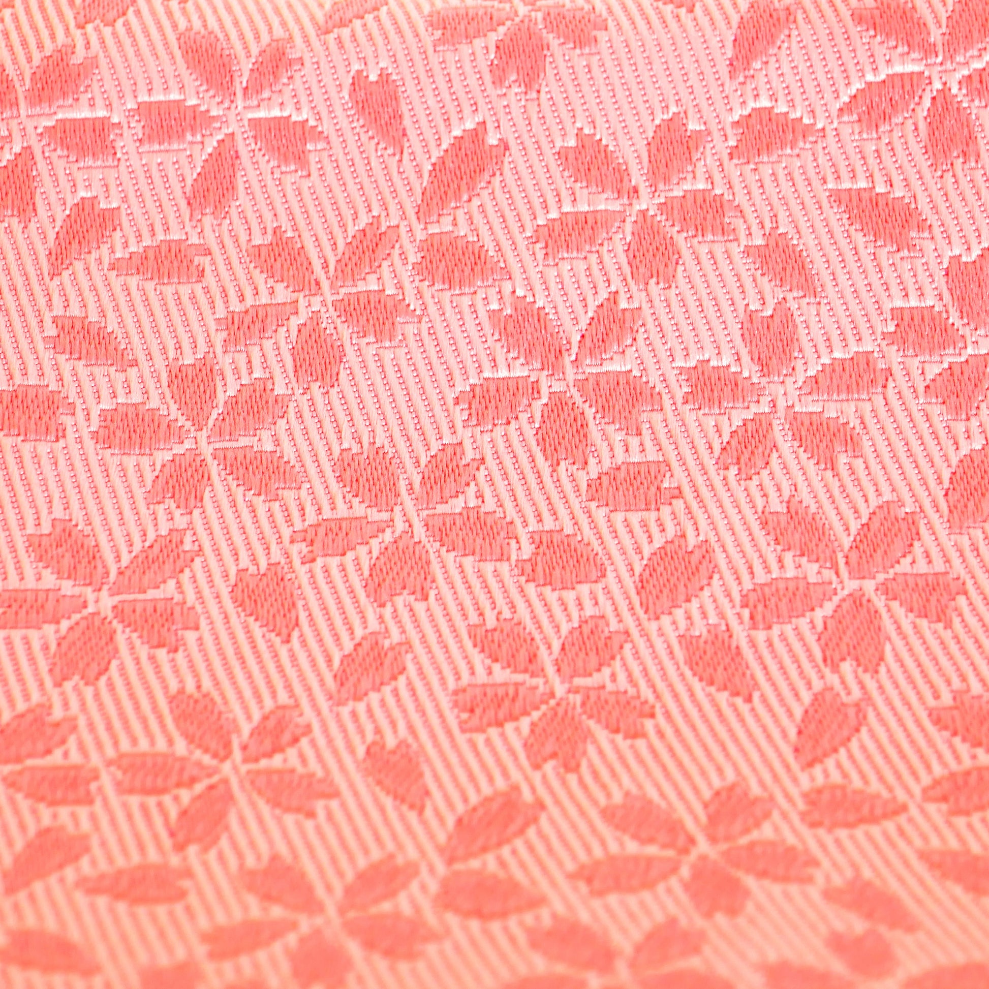 Gros plan sur les fleurs de cerisier en relief d’un obi hanhaba rose.