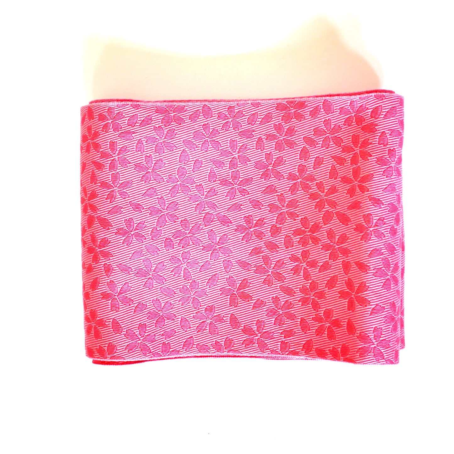 Face pliée d’un hanhaba obi rose avec motifs de fleurs de cerisier.