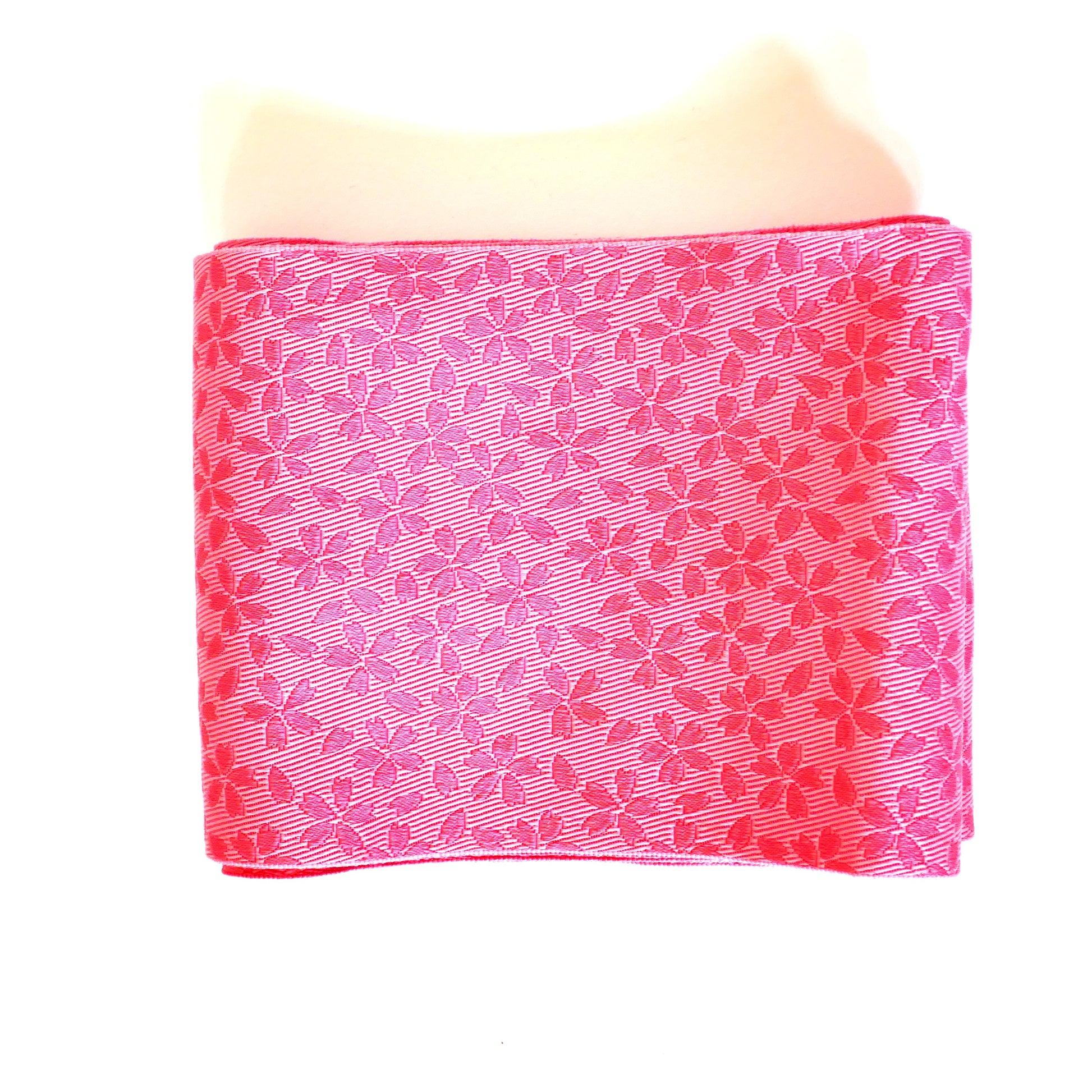 Face pliée d’un hanhaba obi rose avec motifs de fleurs de cerisier.