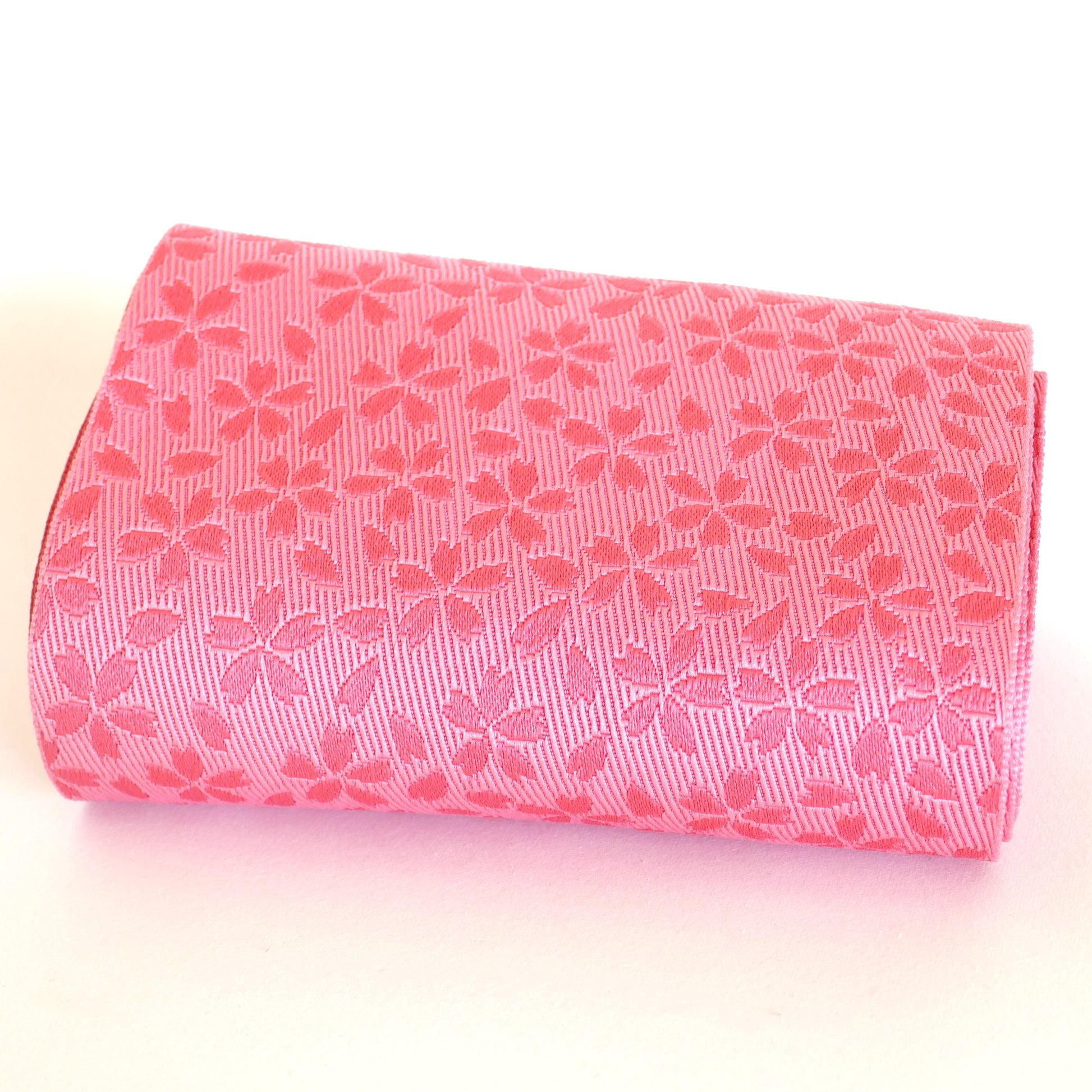 Obi hanhaba rose à motifs sakura, présenté roulé.