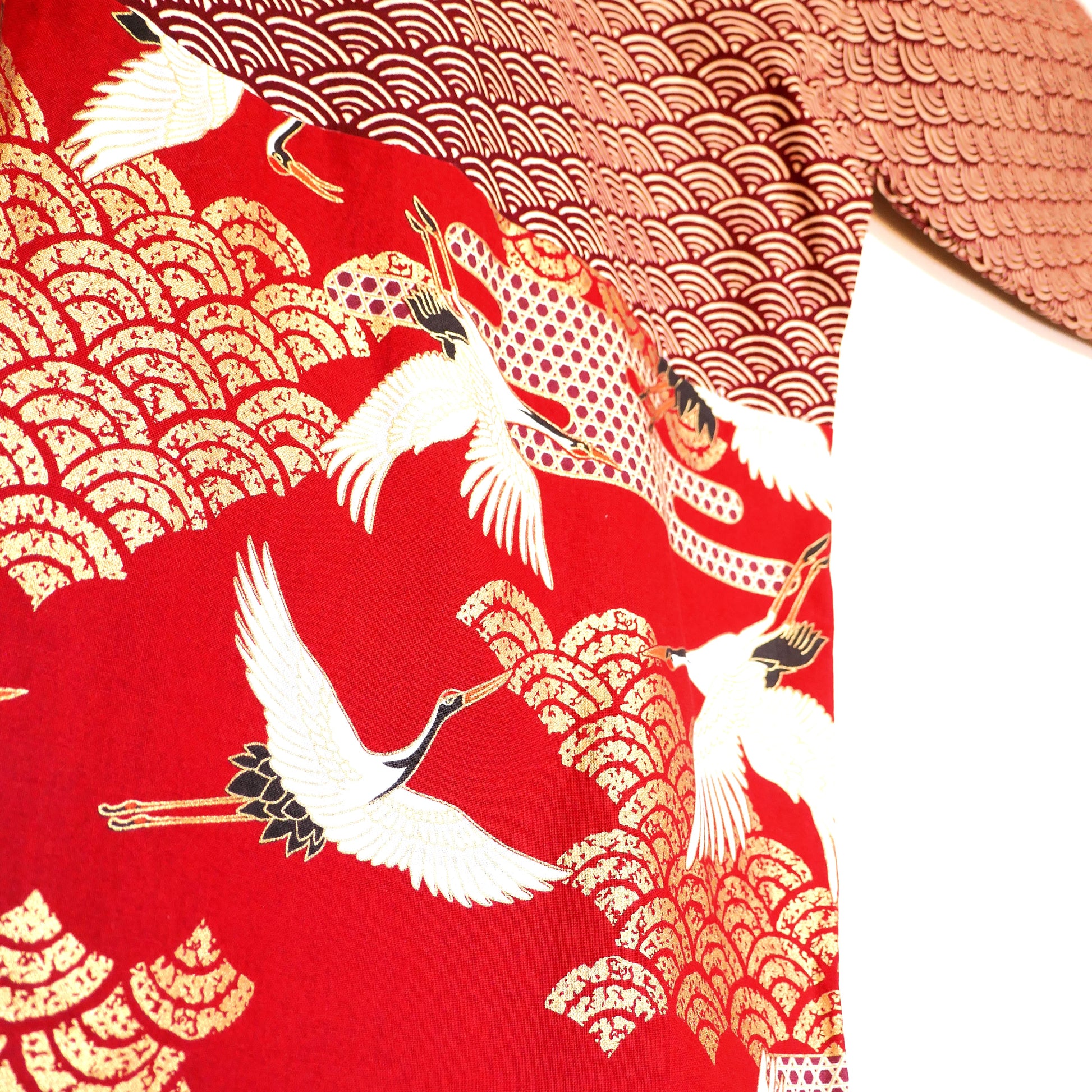 Zoom sur le bas du dos du haori Akane Tsuru, mettant en valeur les grues japonaises blanches volant au-dessus de nuages dorés.