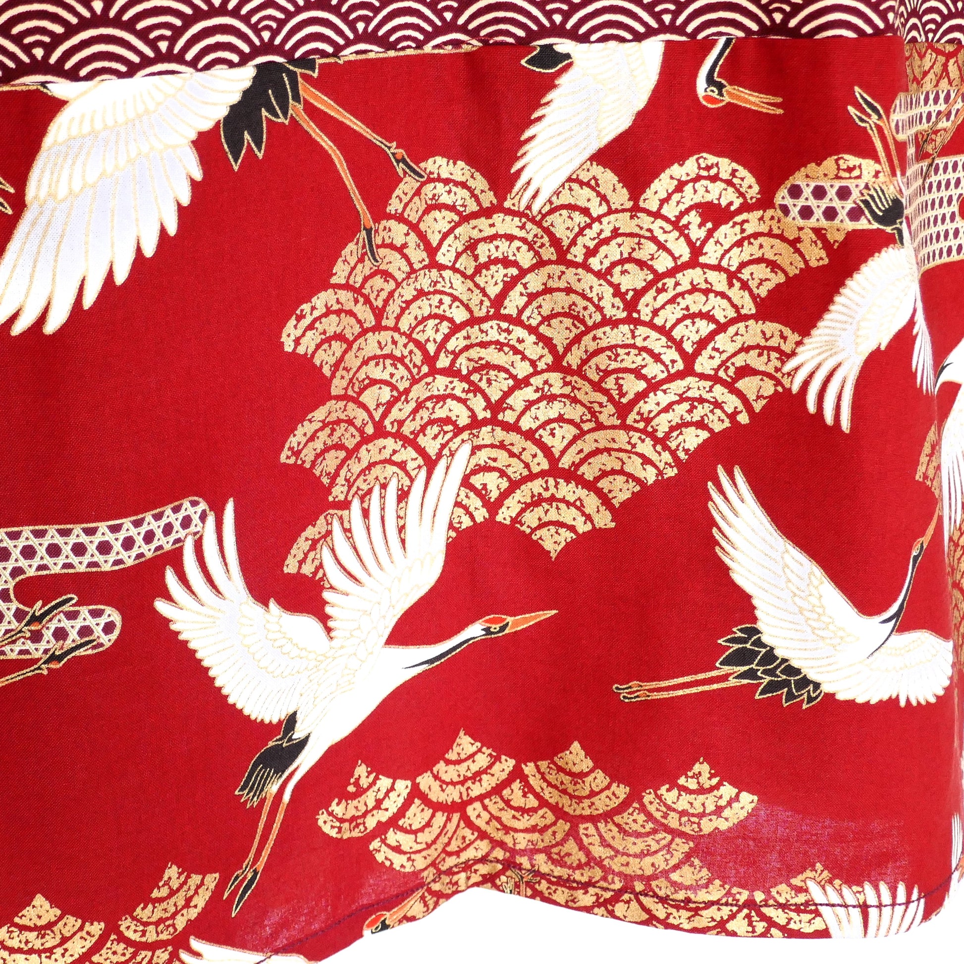 Gros plan sur le col du haori Akane Tsuru, avec tissu rouge carmin orné d’une grue blanche et de nuages dorés stylisés.