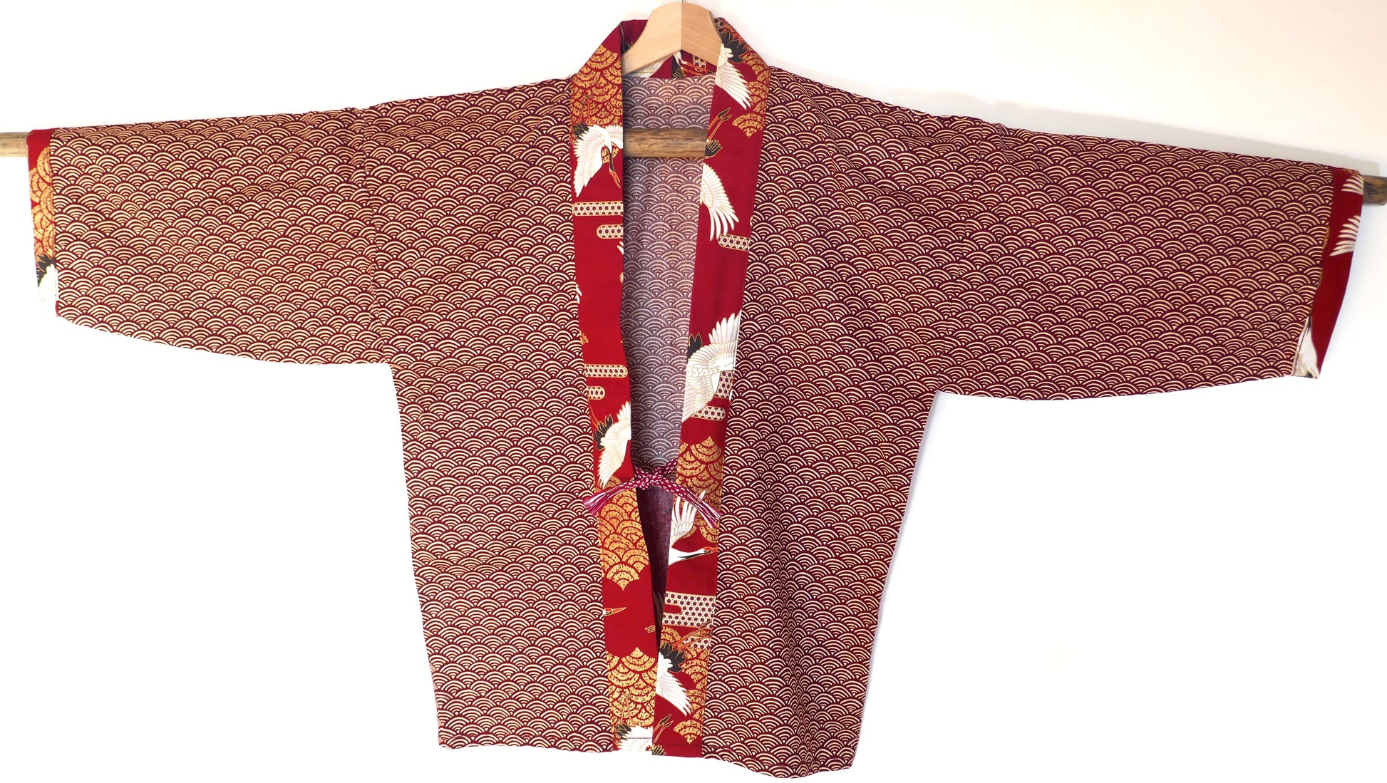 Haori Akane Tsuru vu de face, motifs vagues seigaiha rouge, fermé par un obijime obihimo assorti, avec col à motifs de grues japonaises et fond rouge vif.