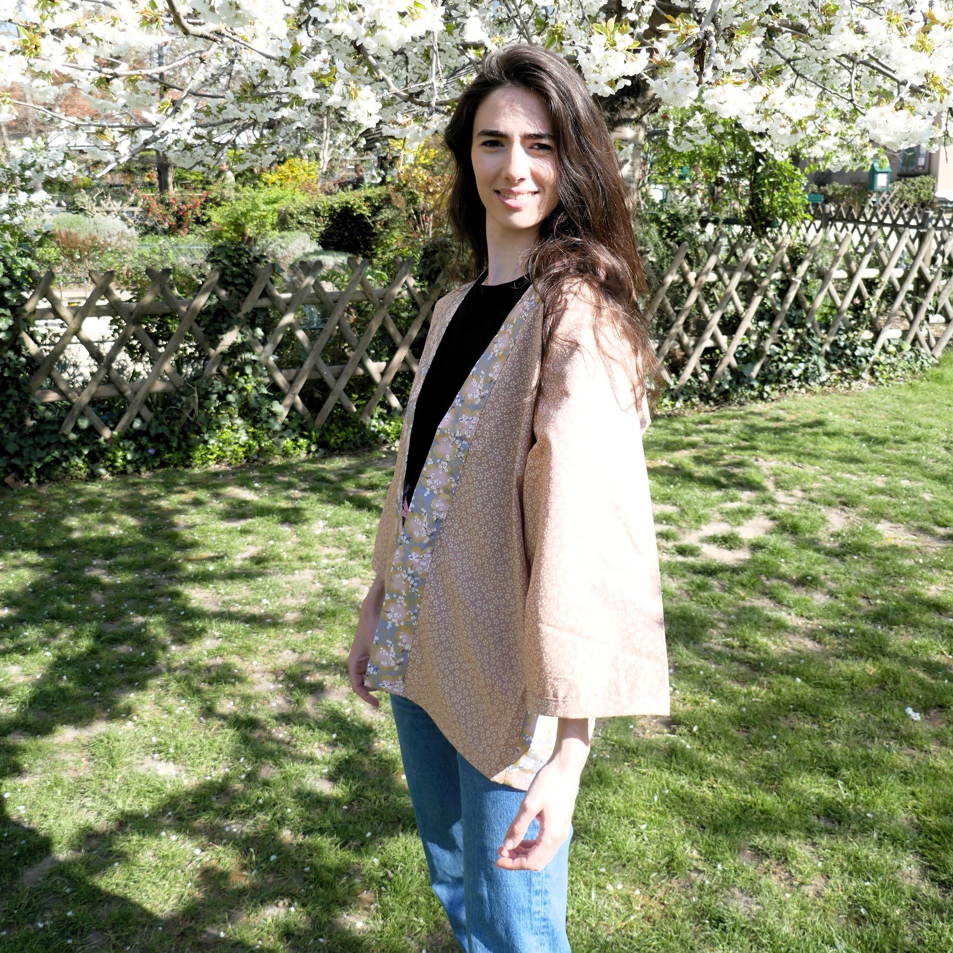 Mayssa porte le haori Hanami bby KOGEDO l'Atelier avec un sourire léger, en harmonie avec les fleurs de cerisier – style doux et printanier.
