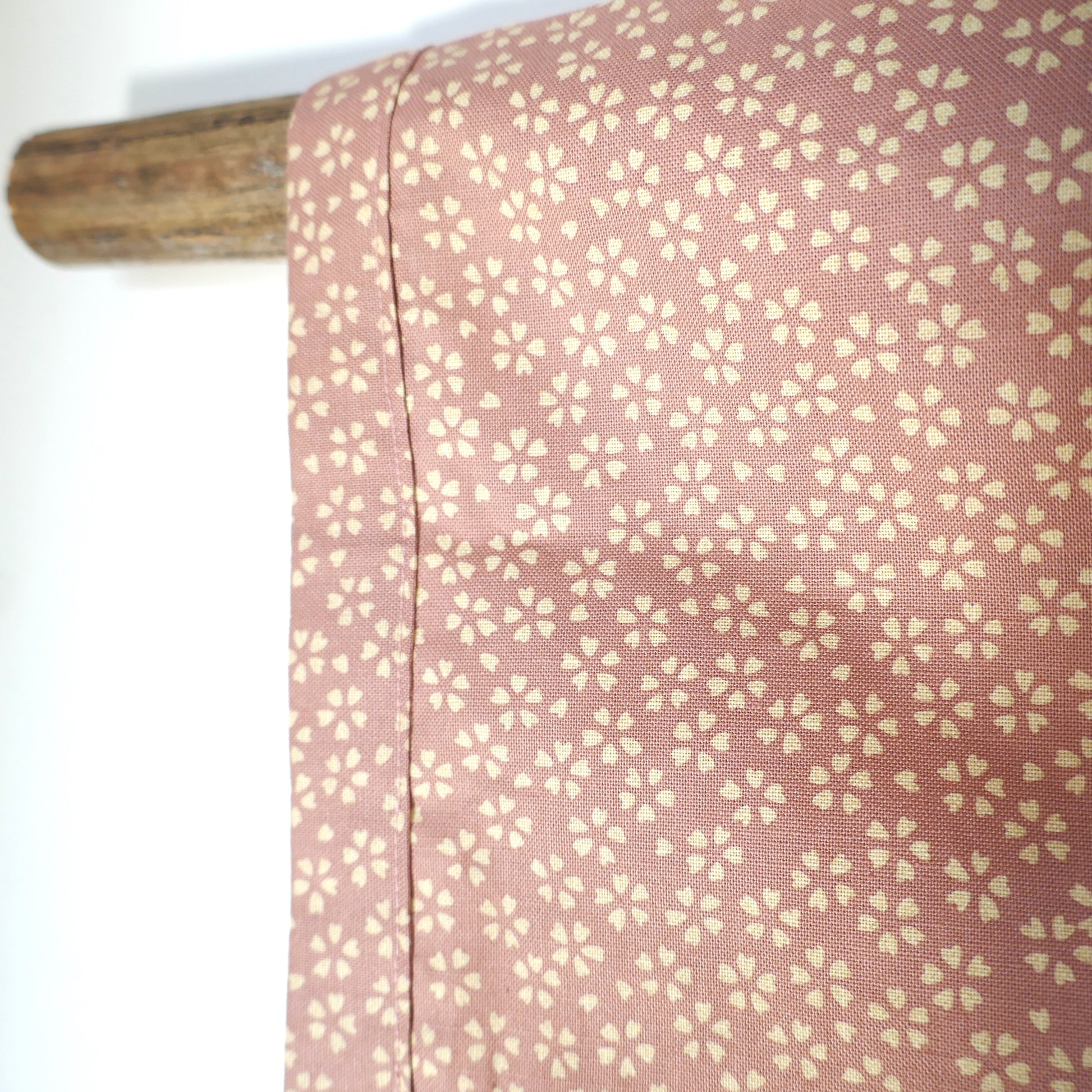 Gros plan sur la manche du haori Hanami, tissu japonais vieux rose à fleurs de cerisier blanches crème.