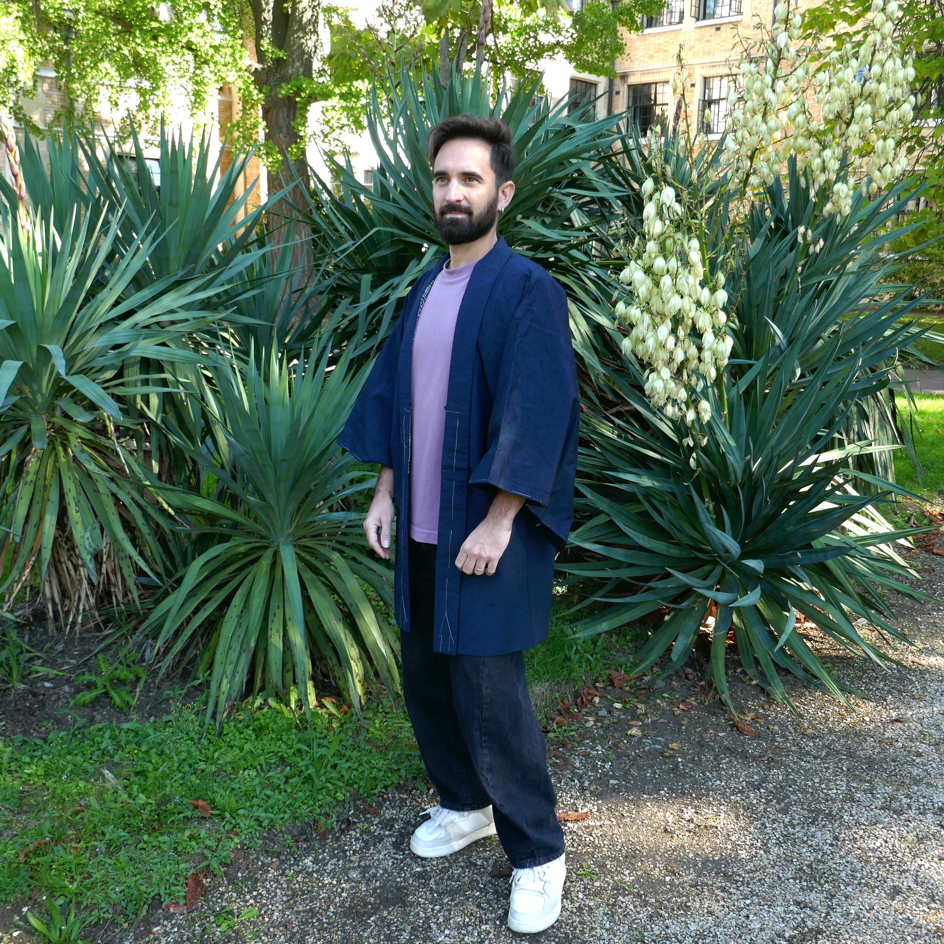 Haori homme vintage en soie bleu indigo porté par Tôma de face dans un jardin