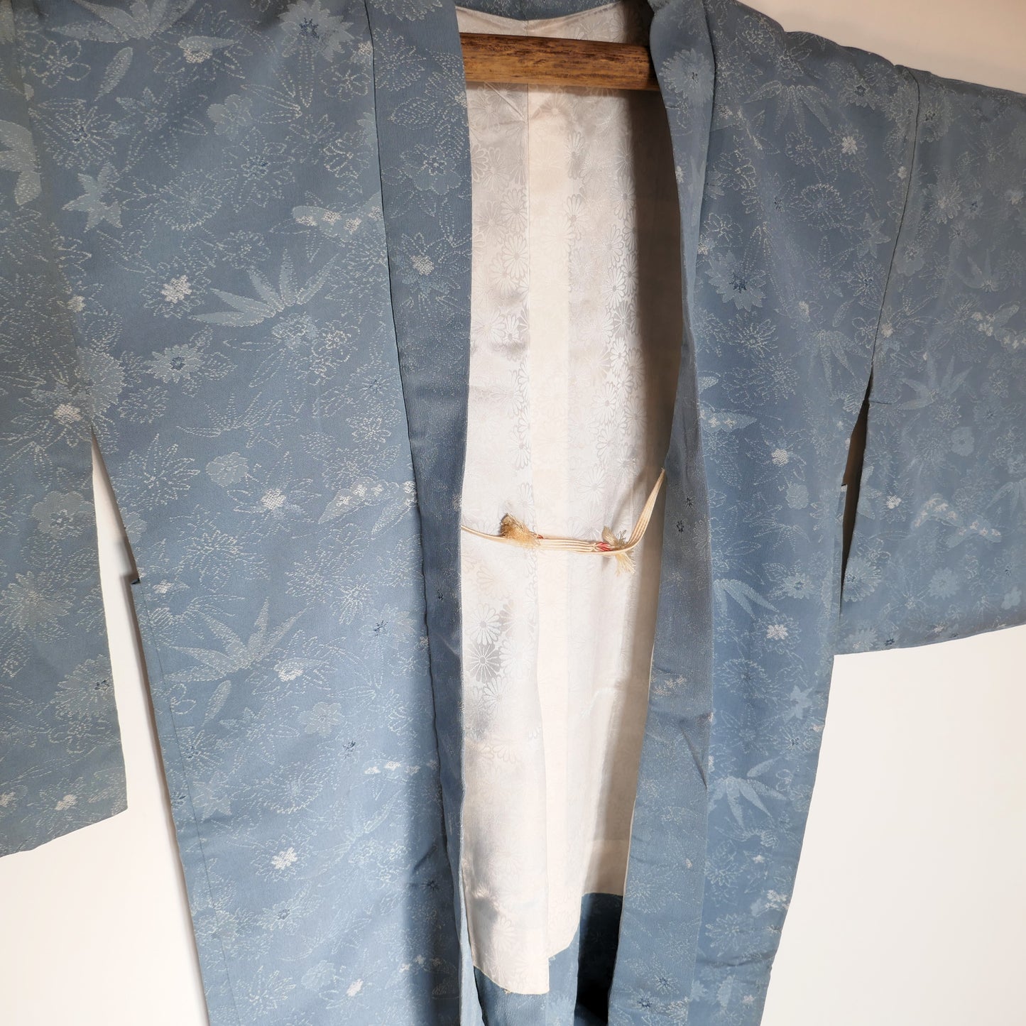 Haori en soie bleu ciel vu de face, ouvert, révélant la doublure blanche à fleurs de chrysanthèmes ton sur ton.