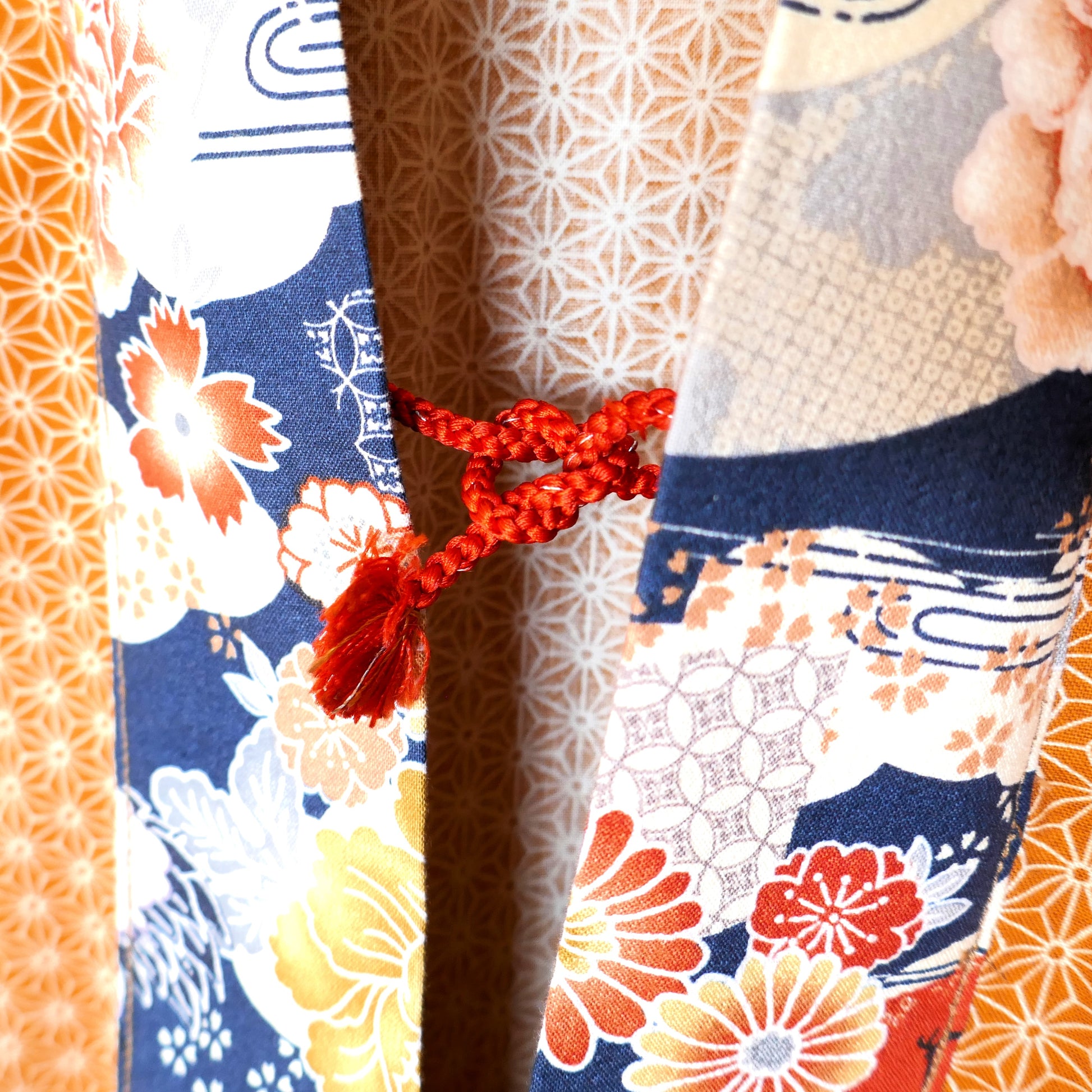 Gros plan sur l'attache haori himo rouge du haori Yūyake Zakura