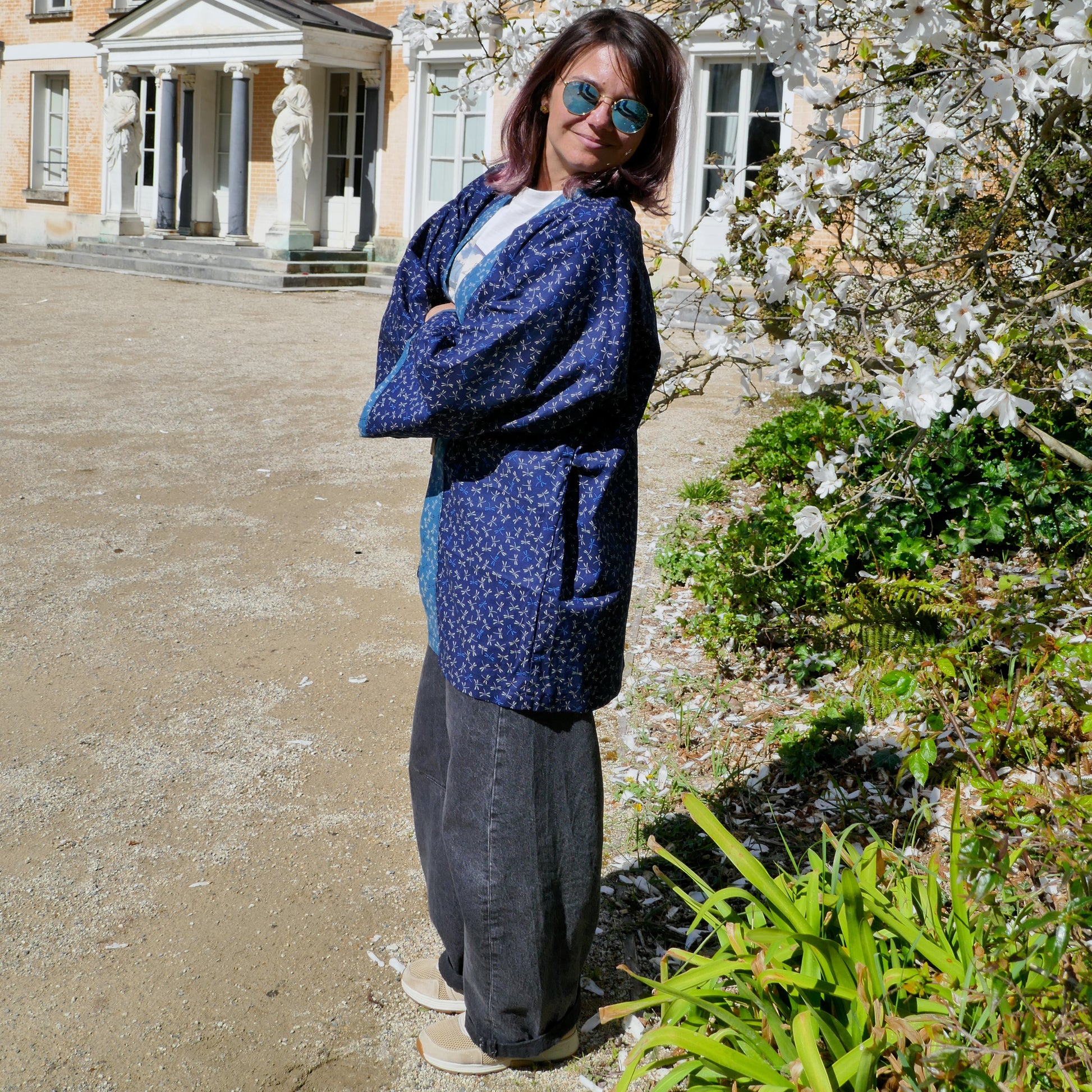 Mikan de profil en haori KOGEDO l'atelier full tombo, debout devant une bâtisse ancienne, vêtement traditionnel japonais revisité.