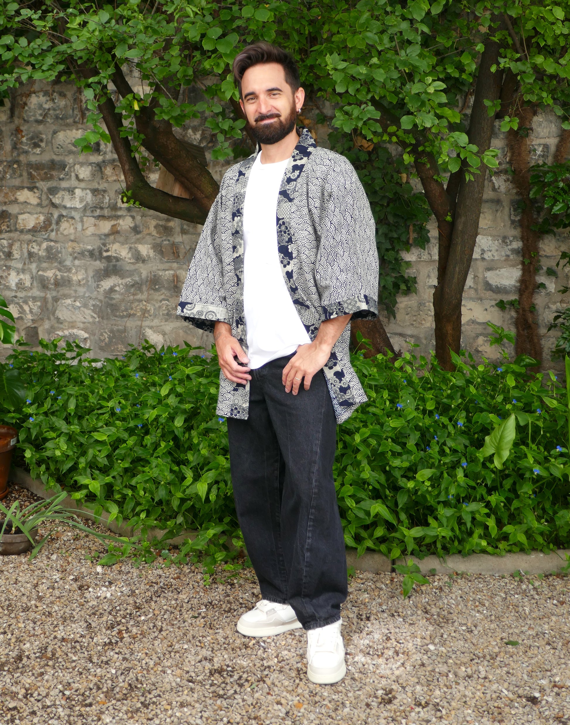 Toma porte le haori “Umi no Sakura” de KOGEDO, style casual avec t-shirt blanc et jean noir. Veste kimono mixte aux imprimés seigaiha et détails floraux, pour une silhouette moderne et japonaise.