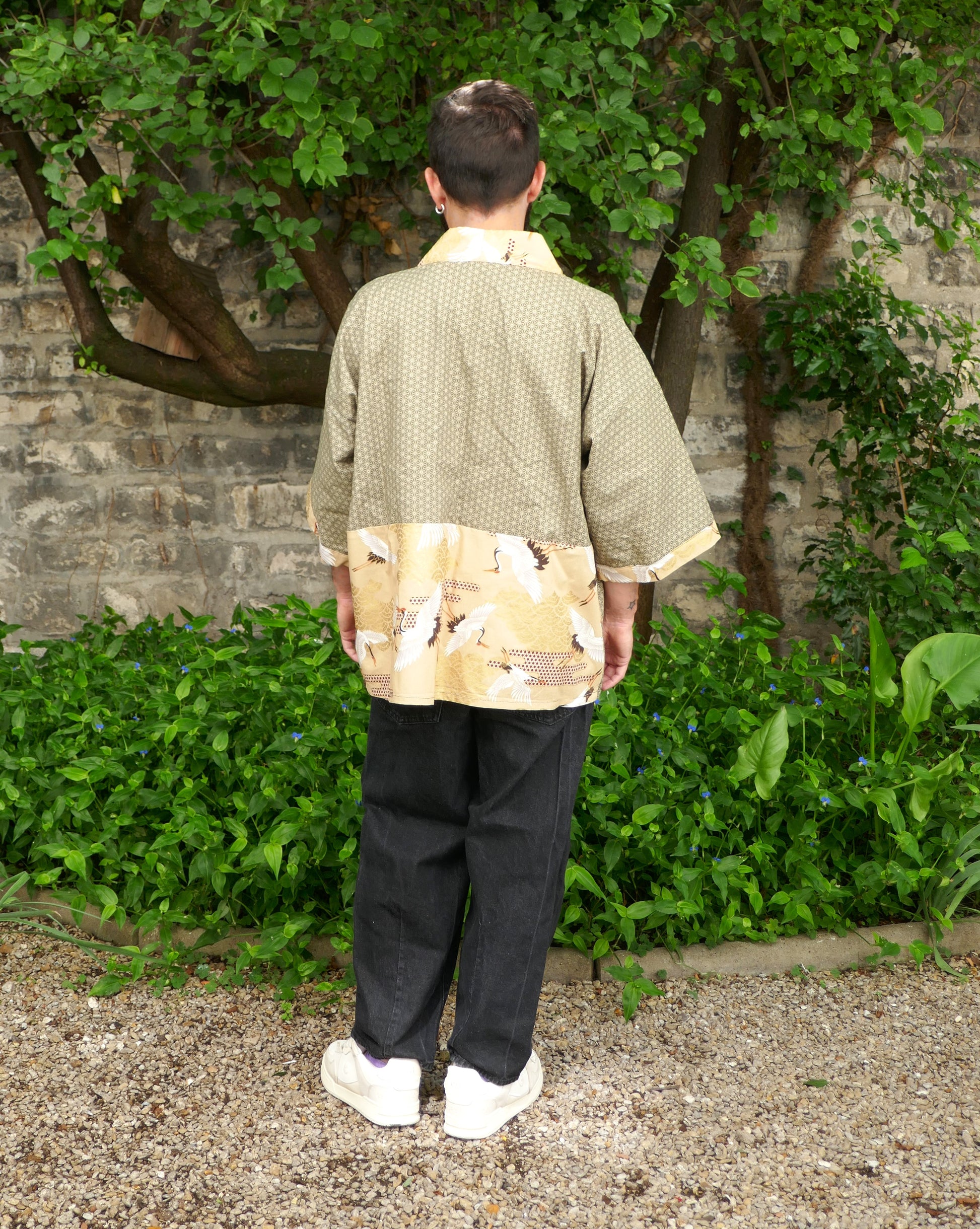 Toma vu de dos portant un haori kimono japonais moderne de l’atelier KOGEDO. Design mixte avec imprimé traditionnel japonais de grues blanches sur fond doré et motif géométrique asanoha kaki.