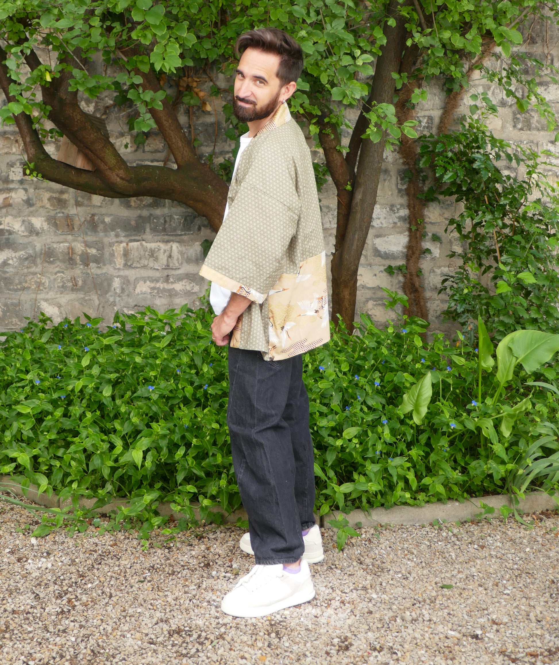 Toma en profil souriant avec le haori "Nohara no Tsuru" de KOGEDO, veste kimono ample inspirée des textiles japonais traditionnels, imprimé d’oiseaux japonais (tsuru) et motif asanoha. Look casual chic pour homme.
📸 6. Mikan – vue de trois quarts
Texte alternatif SEO :
Mikan vue de trois quarts portant le haori "Nohara no Tsuru", veste kimono de fabrication artisanale KOGEDO. Tissu japonais aux grues blanches et motif géométrique vert, look doux et naturel dans un jardin verdoyant.
Souhaites-tu que je t’