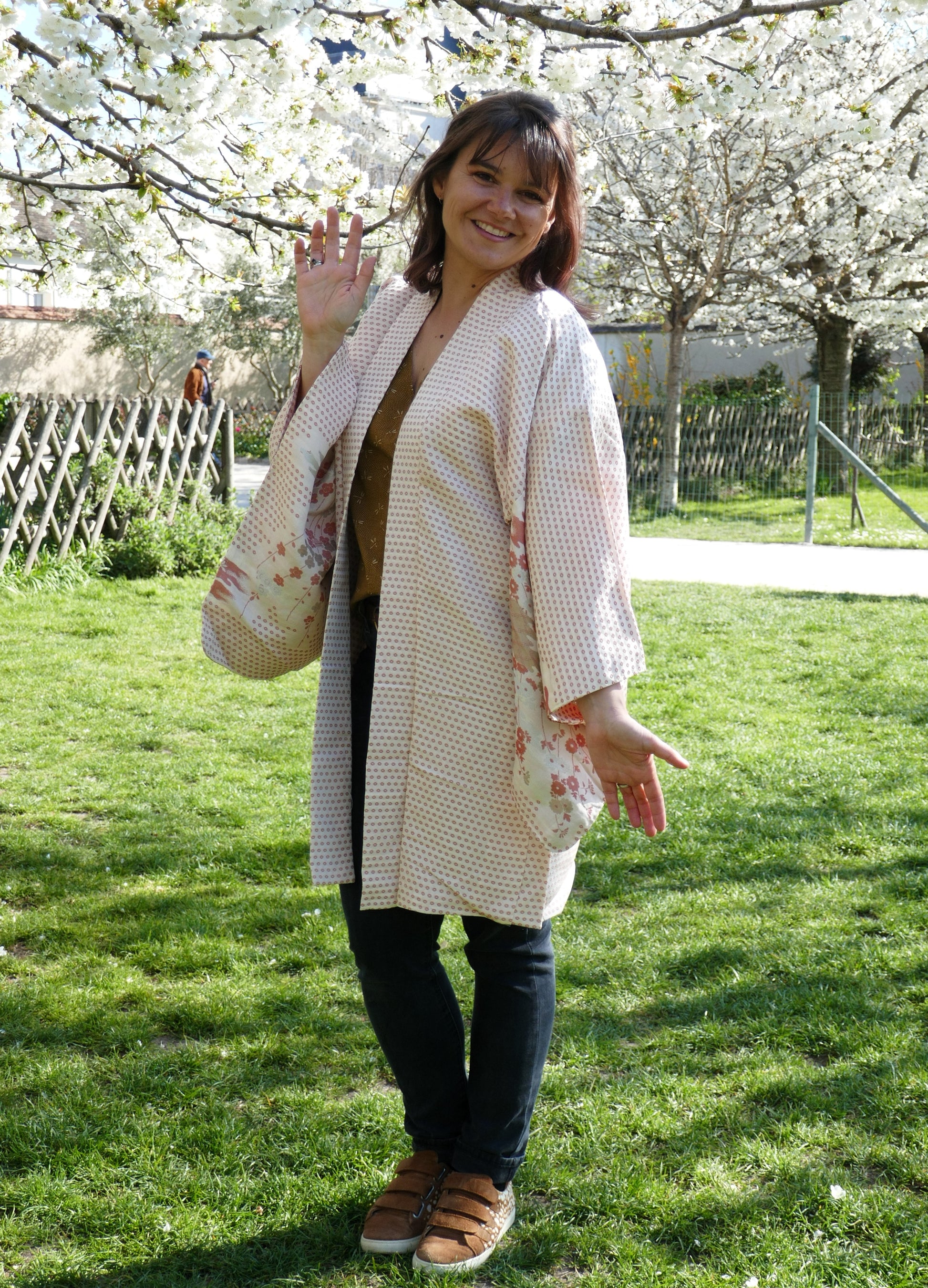 Haori ancien en soie à motif de fleurs de saison porté par Mikan, vue de face dans un jardin au printemps.