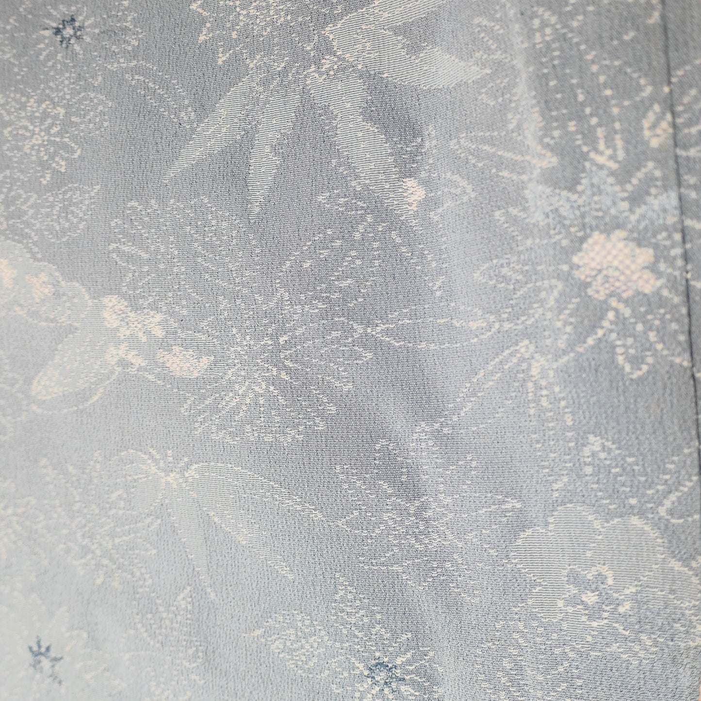 Détail des motifs floraux et feuillages sur le tissu bleu clair du haori, en soie ancienne japonaise.