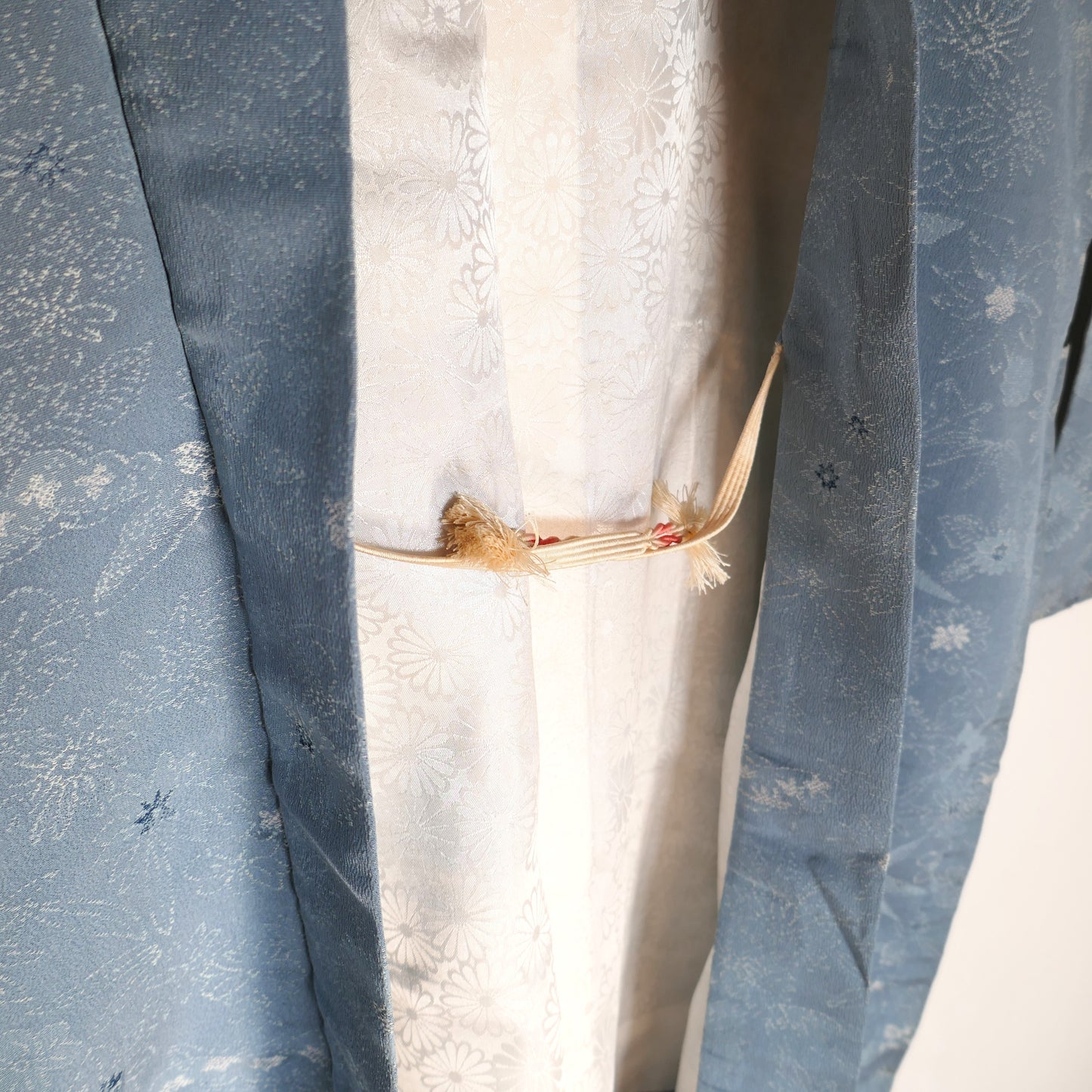 Détail du col d’un haori vintage en soie bleu ciel, avec des motifs tissés de feuilles de bambou et fleurs japonaises.