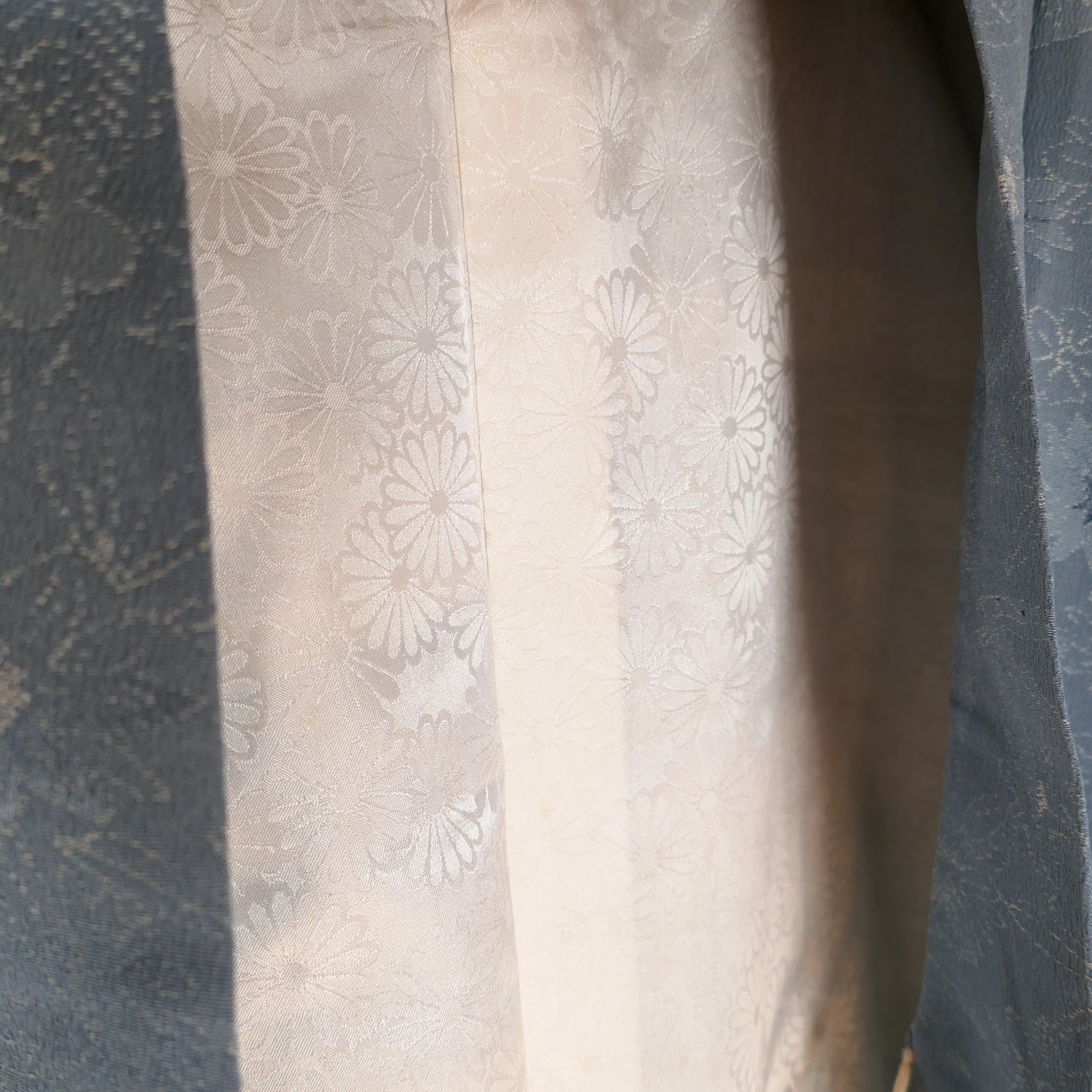 Zoom sur la doublure intérieure du haori, en soie blanche décorée de chrysanthèmes japonais (kiku 菊) ton sur ton.