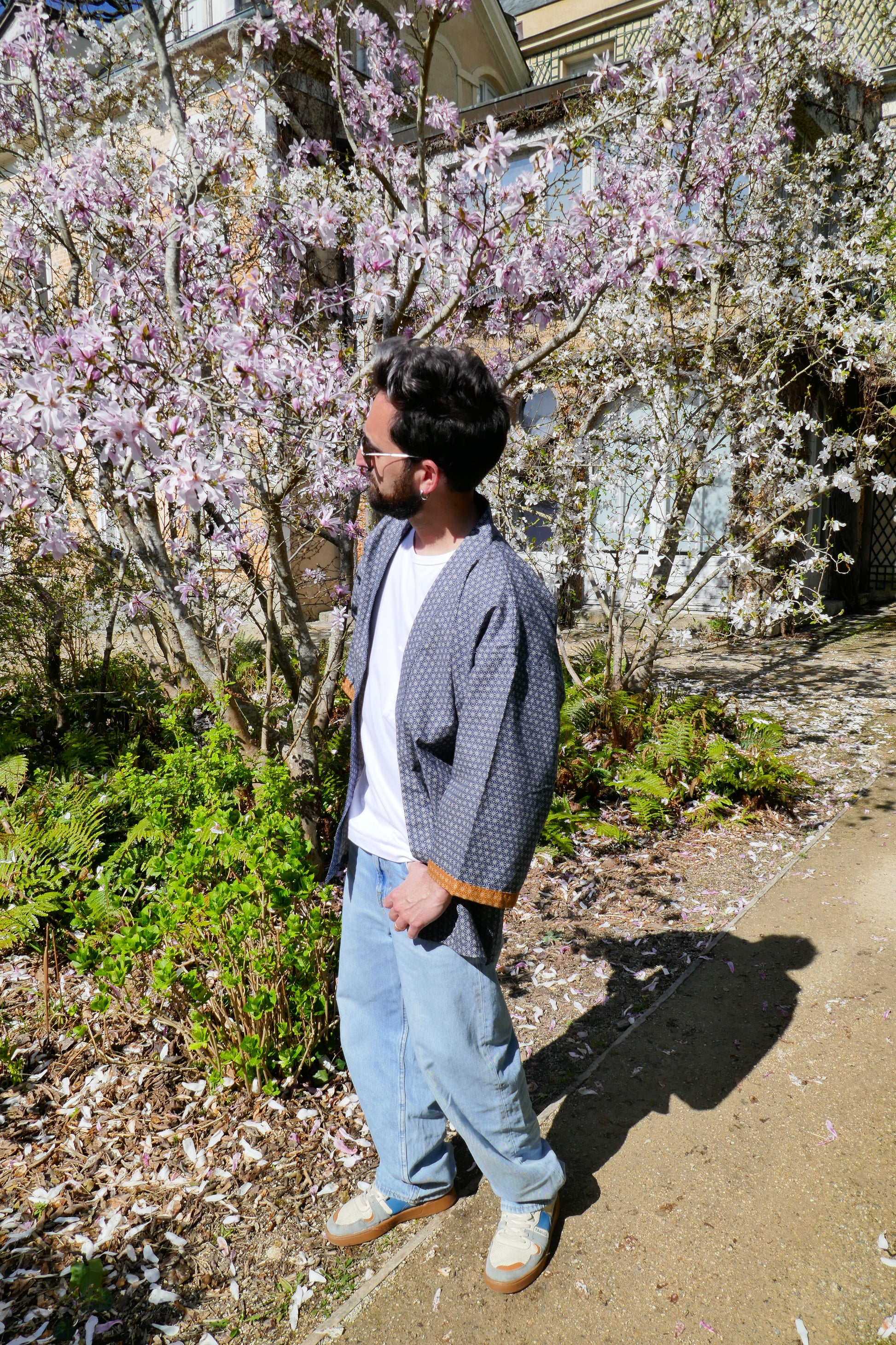 Portrait de Tôma en haori Tradi Tradi devant un magnolia en fleurs, look oversize chic et décontracté.
