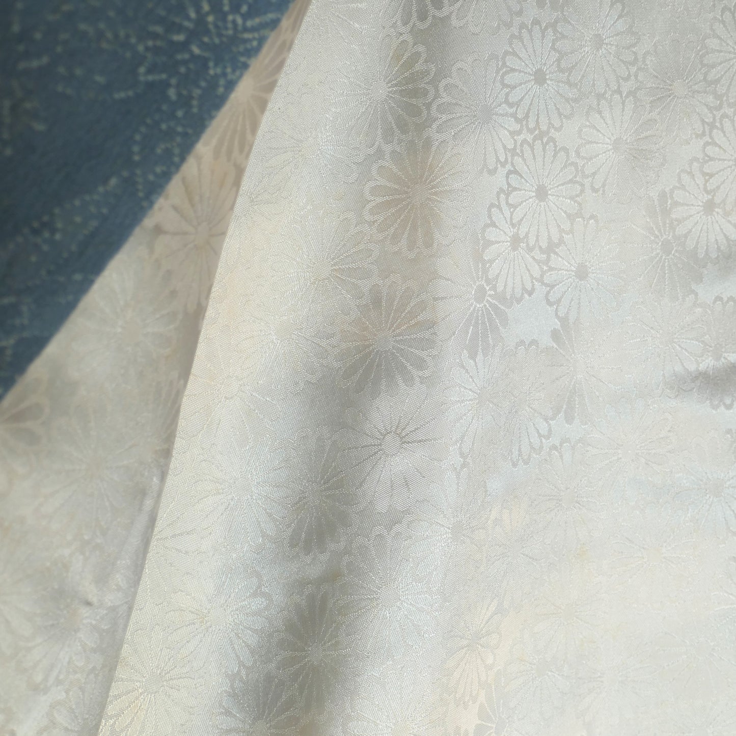 Zoom sur l’intérieur du haori, montrant les motifs raffinés de chrysanthèmes japonais (kiku 菊) sur fond ivoire.